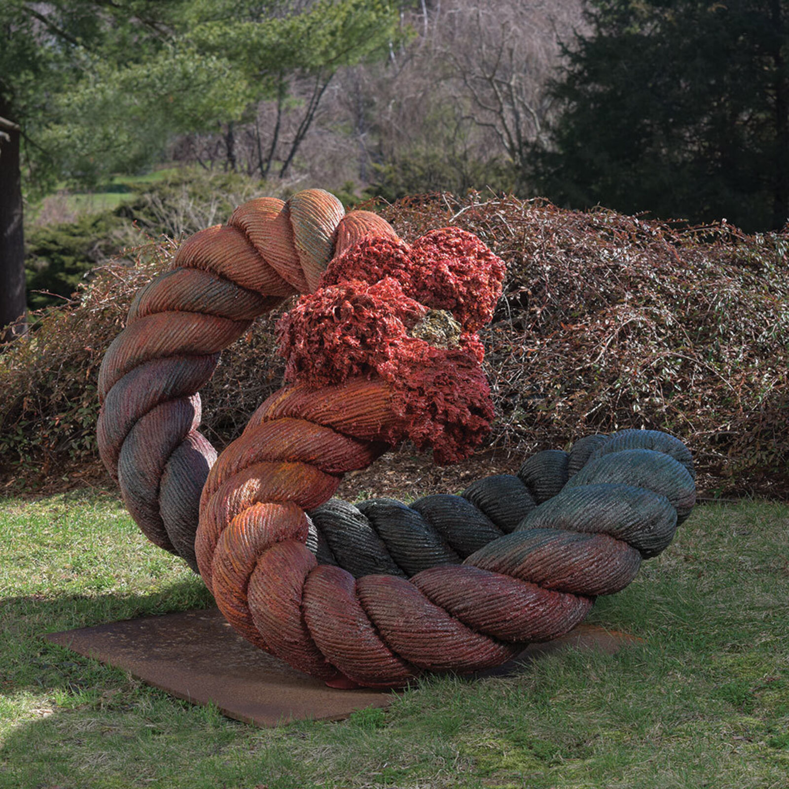 A sculpture of a twisted rope in the middle of a grassy area.