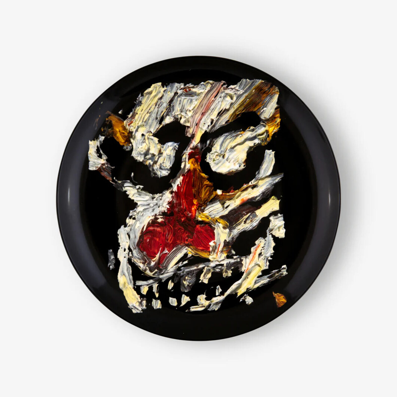 A black plate with a painting of a skull on it.