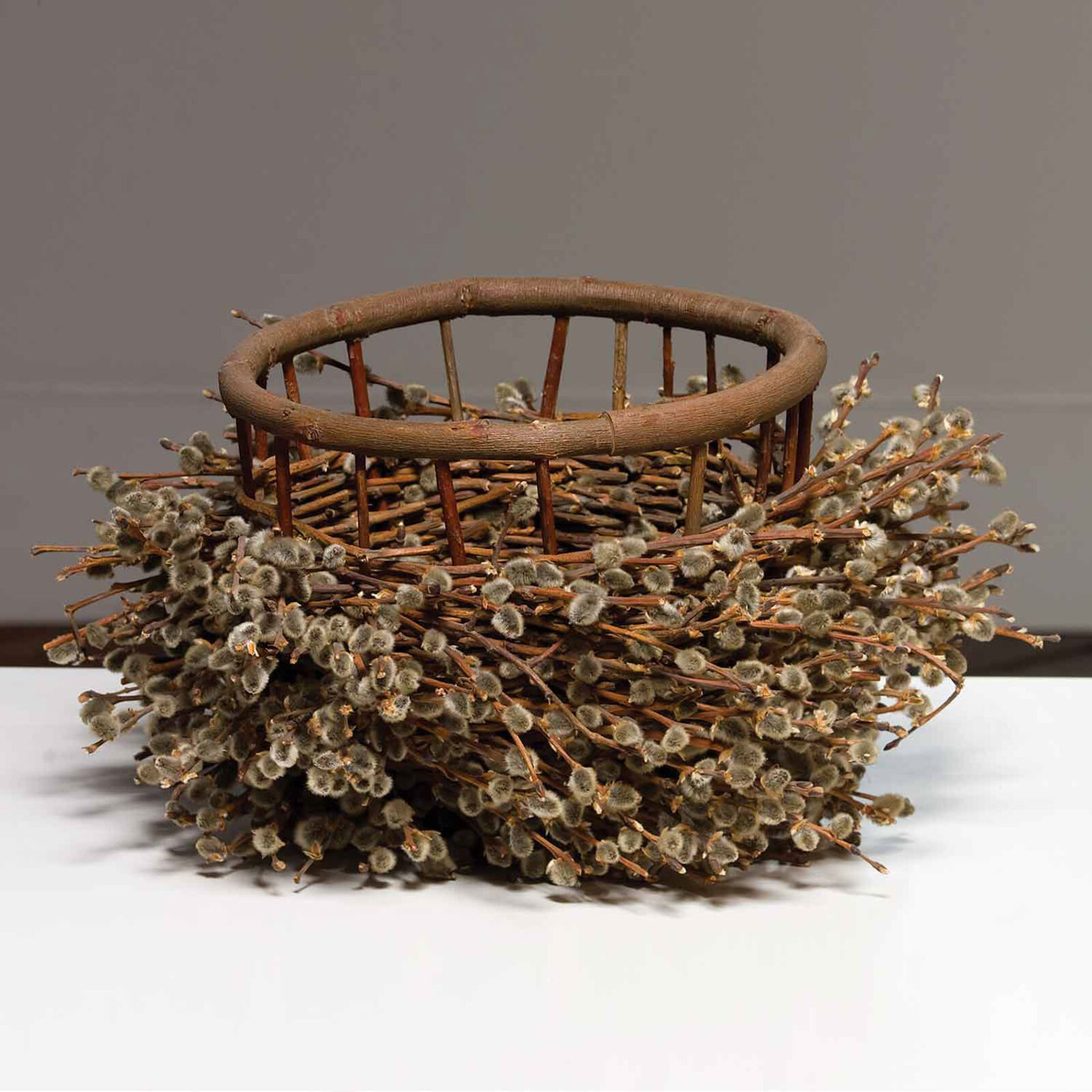 A basket filled with willow branches on top of a table.