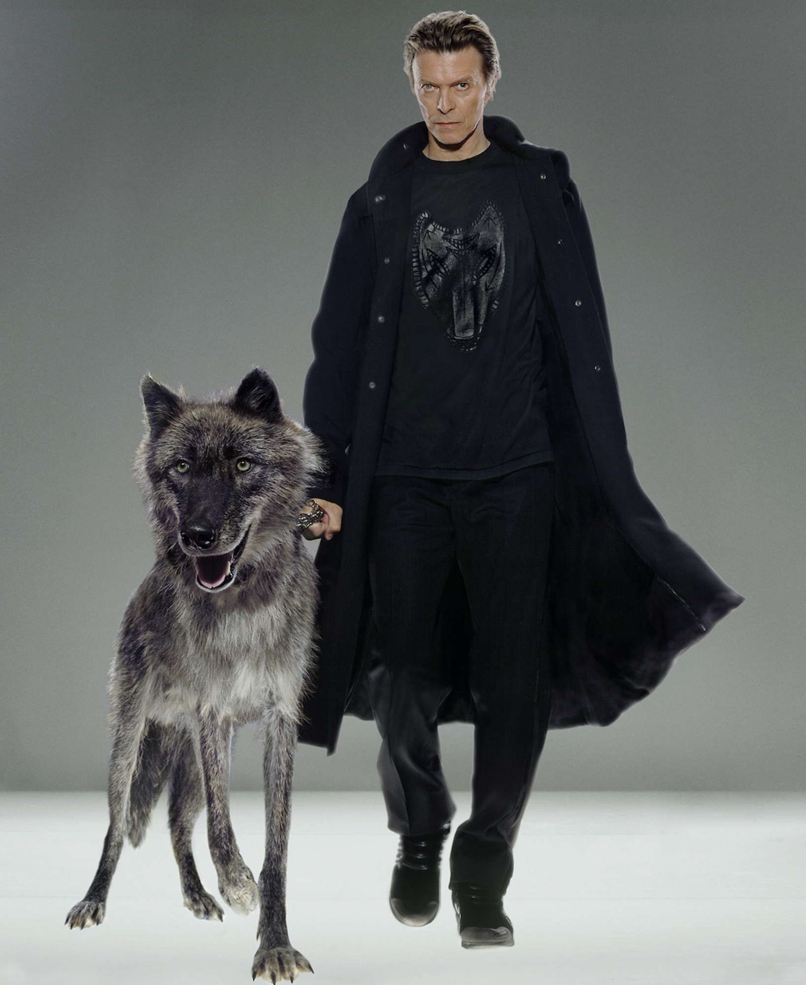 A man walking with a wolf on a runway.