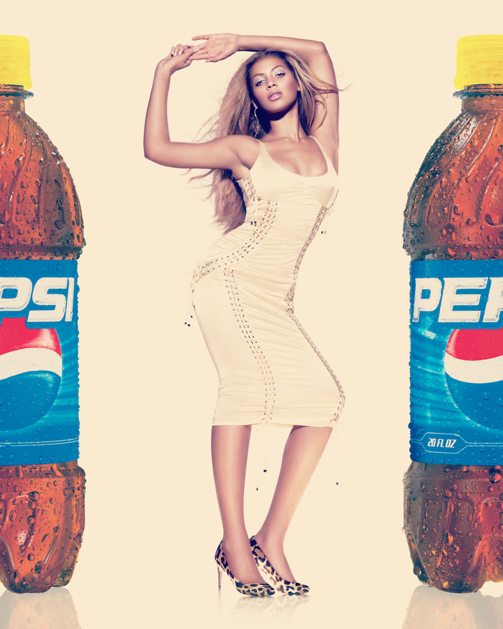 A woman in a white dress standing next to two bottles of Pepsi.