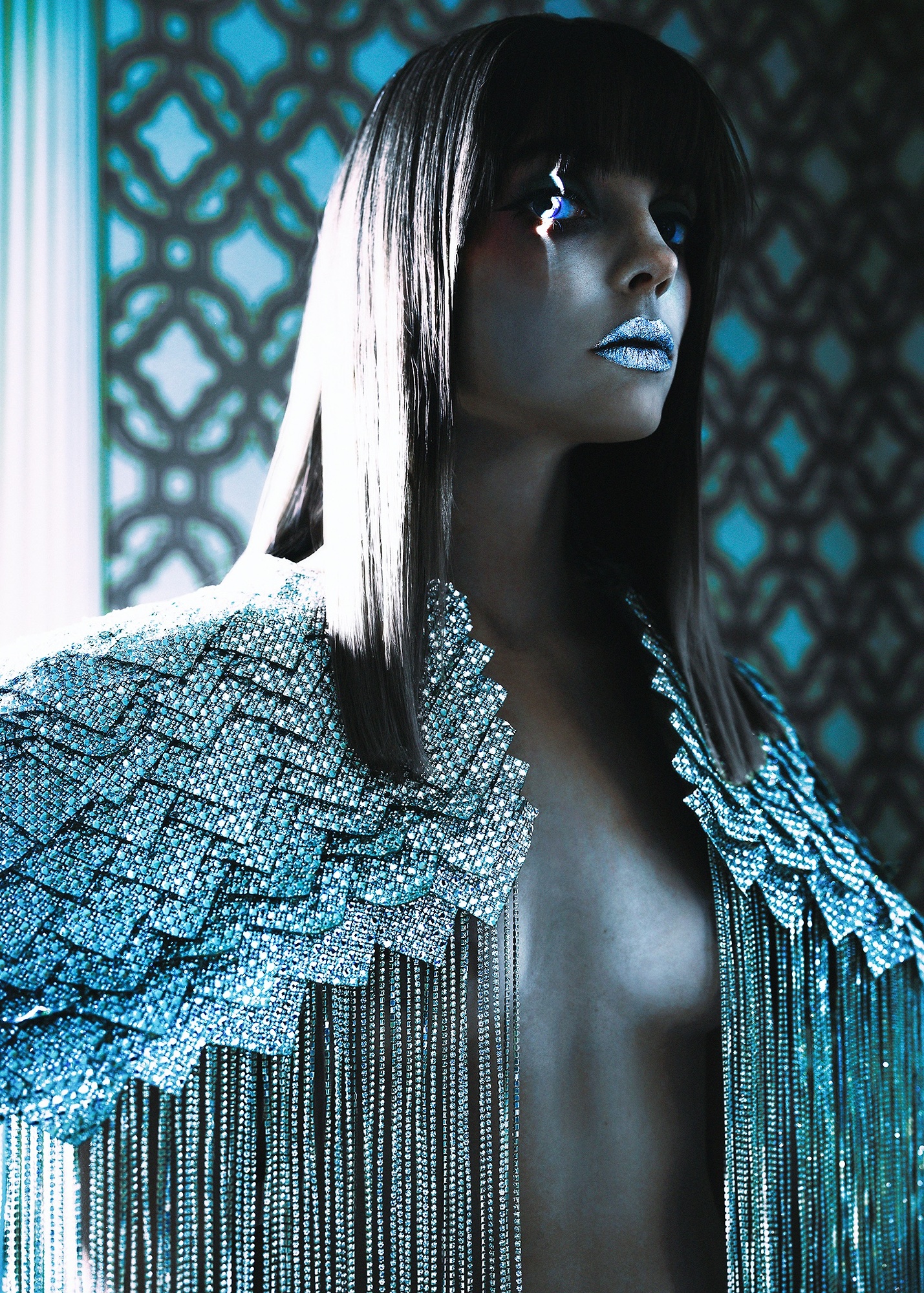 A woman with long black hair wearing a silver jacket.