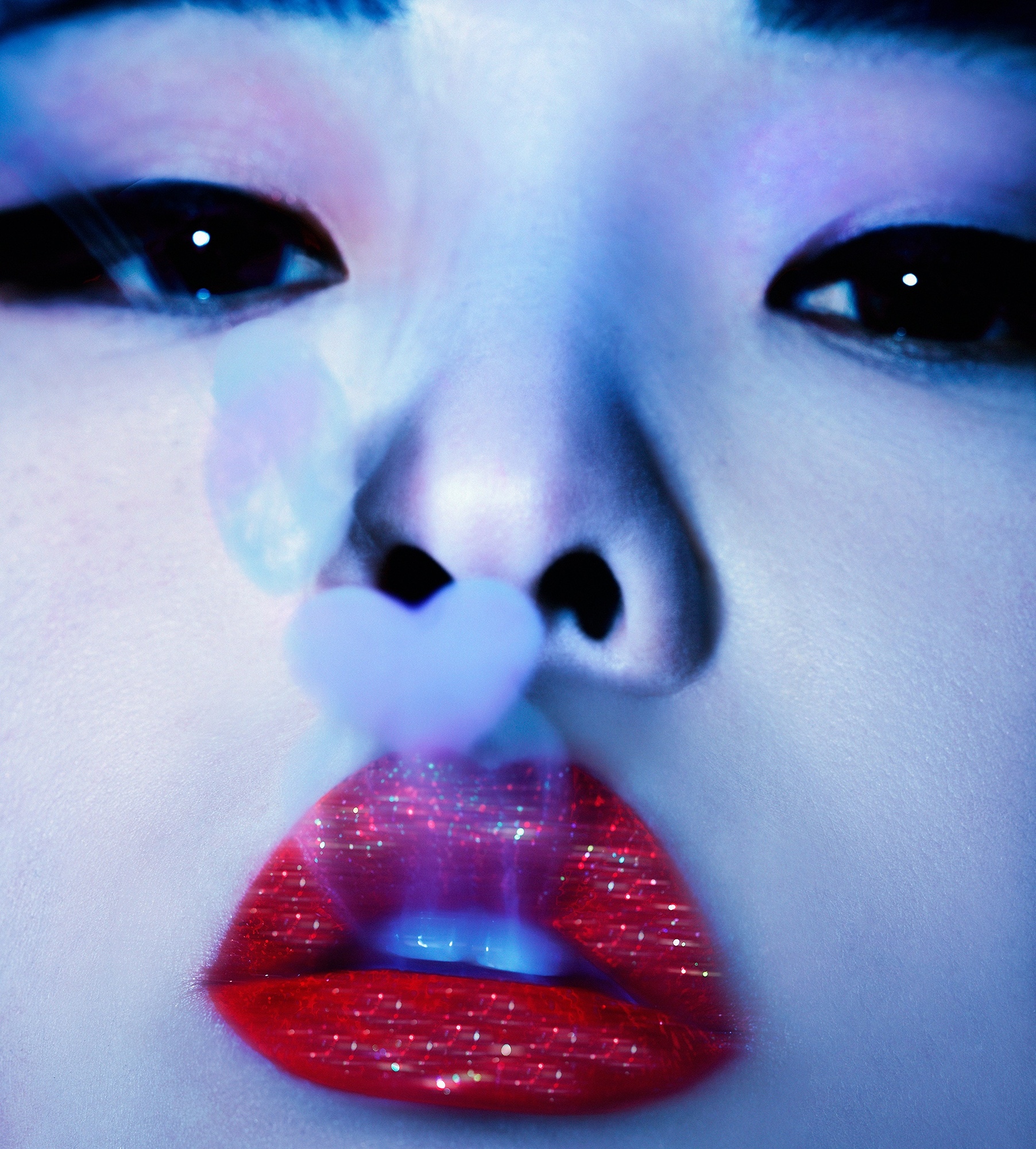A close up of a woman's face with a heart shaped object in her mouth.