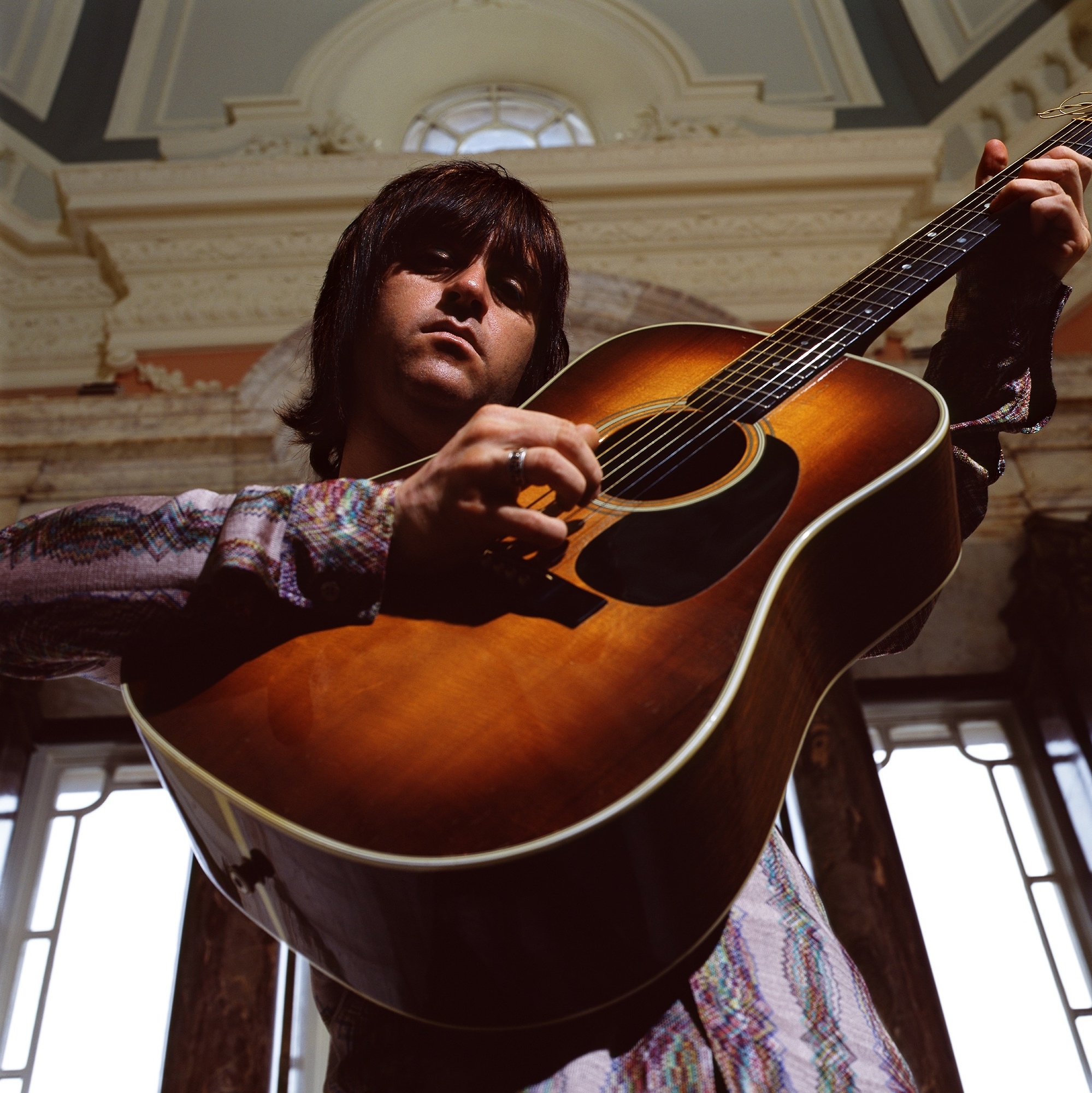 A man holding a guitar in a room.