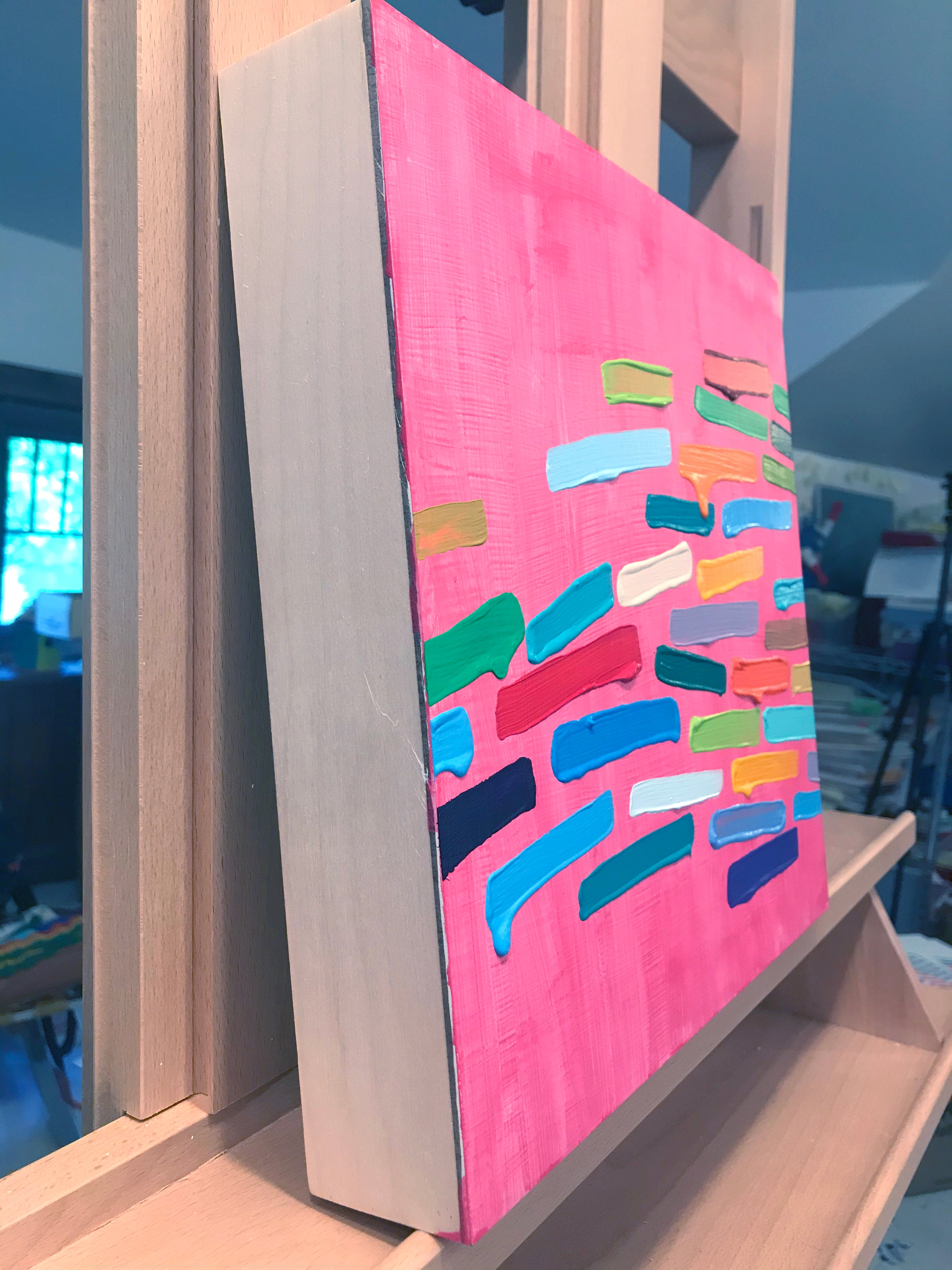 A painting of colorful paint strokes on a pink background.