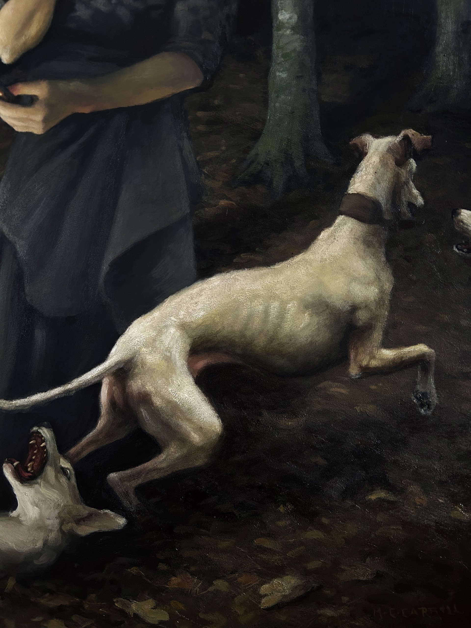 A woman standing in a forest with two dogs and a cell phone.