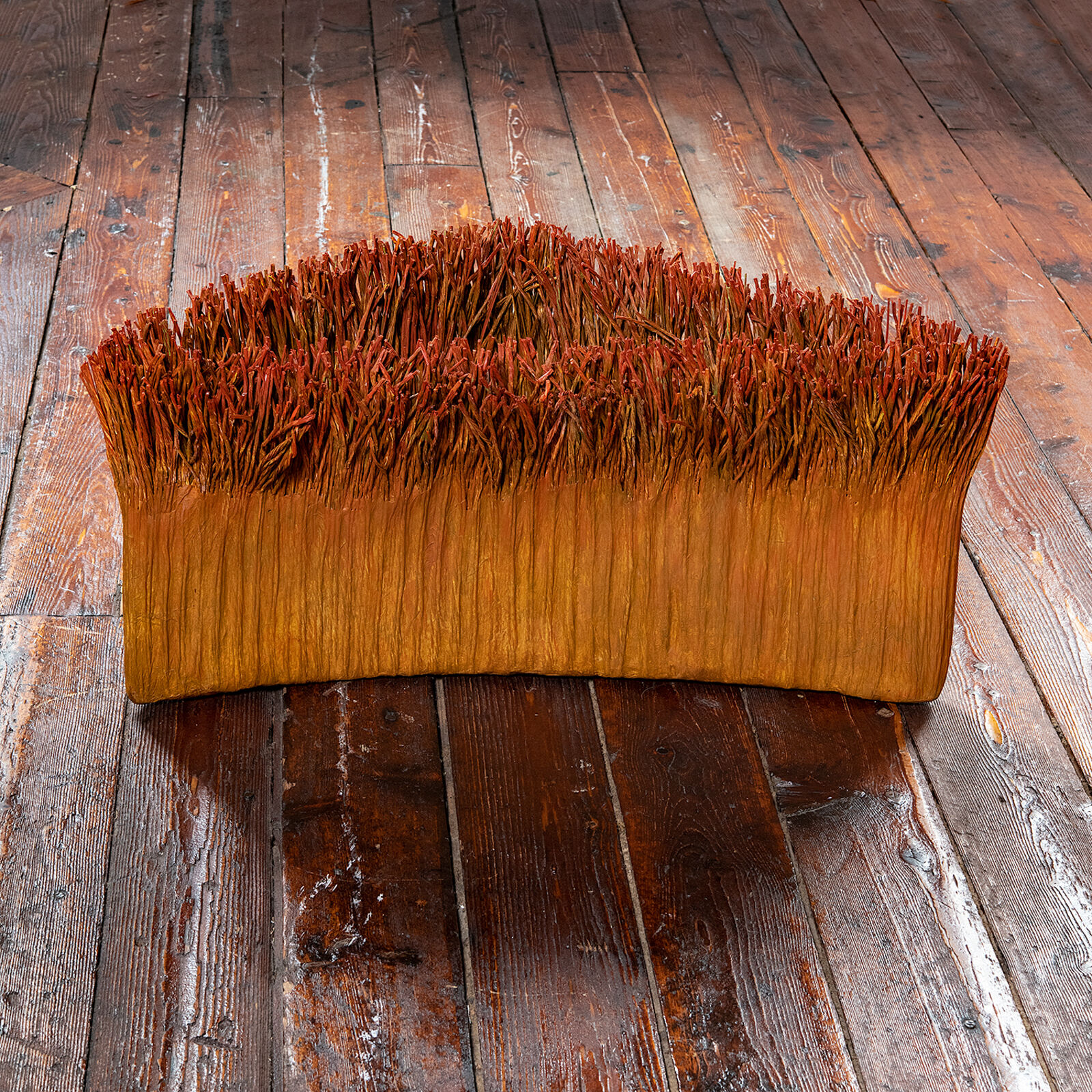 A sculptural piece resembling a miniature grassy mound with a smooth, curved base.