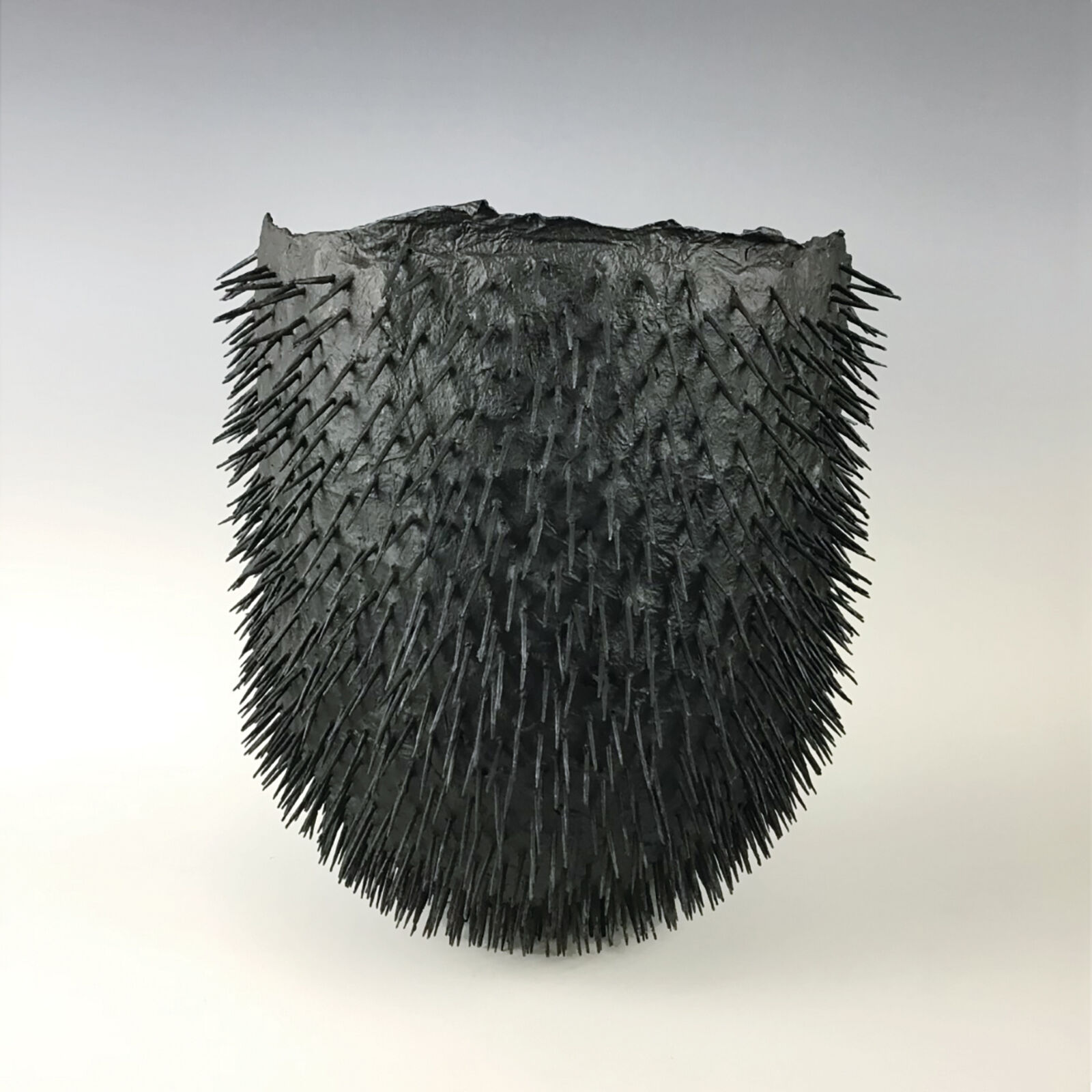 A black sculpture of spikes on a white surface.
