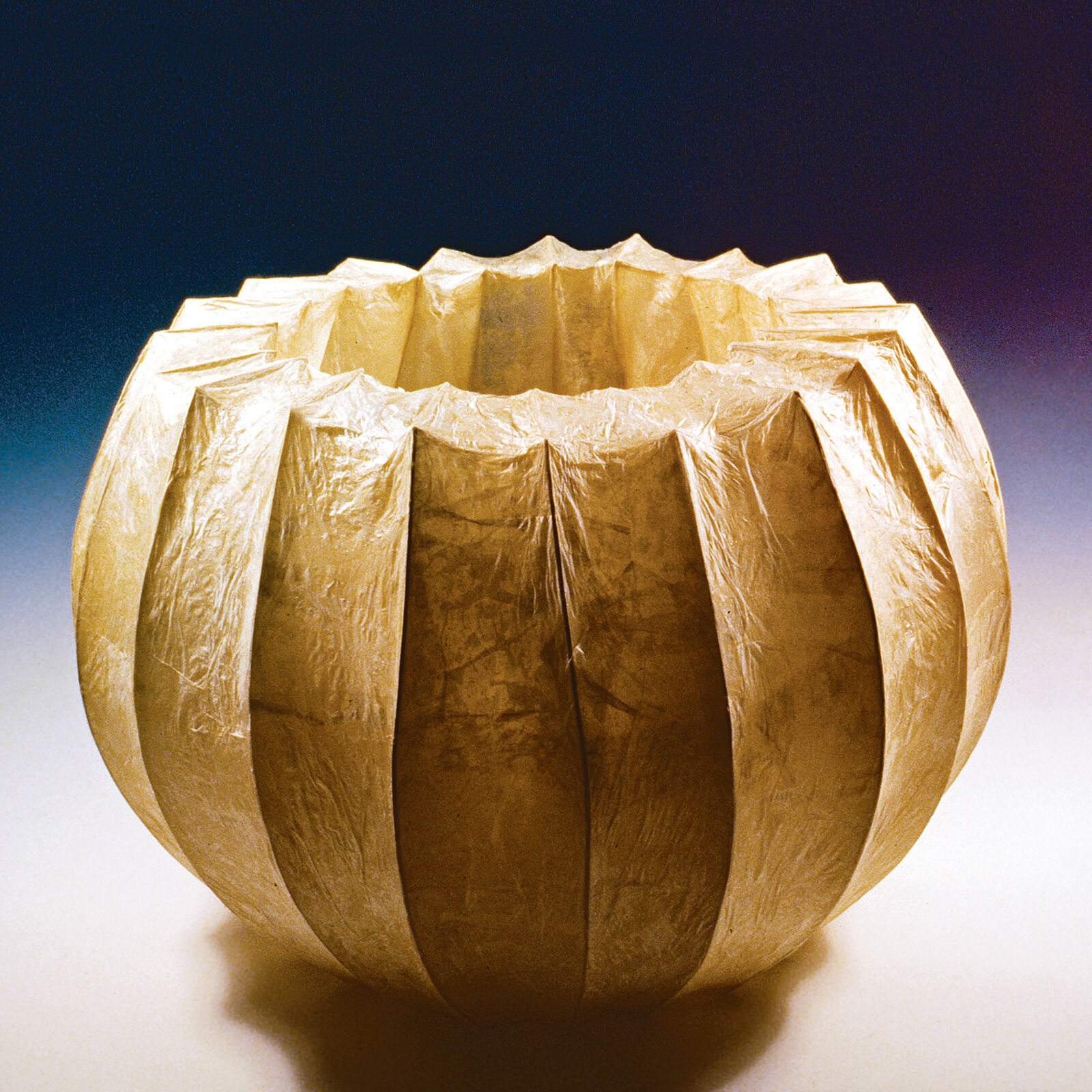 A golden, ribbed vessel with a crinkled texture and a dark blue background.
