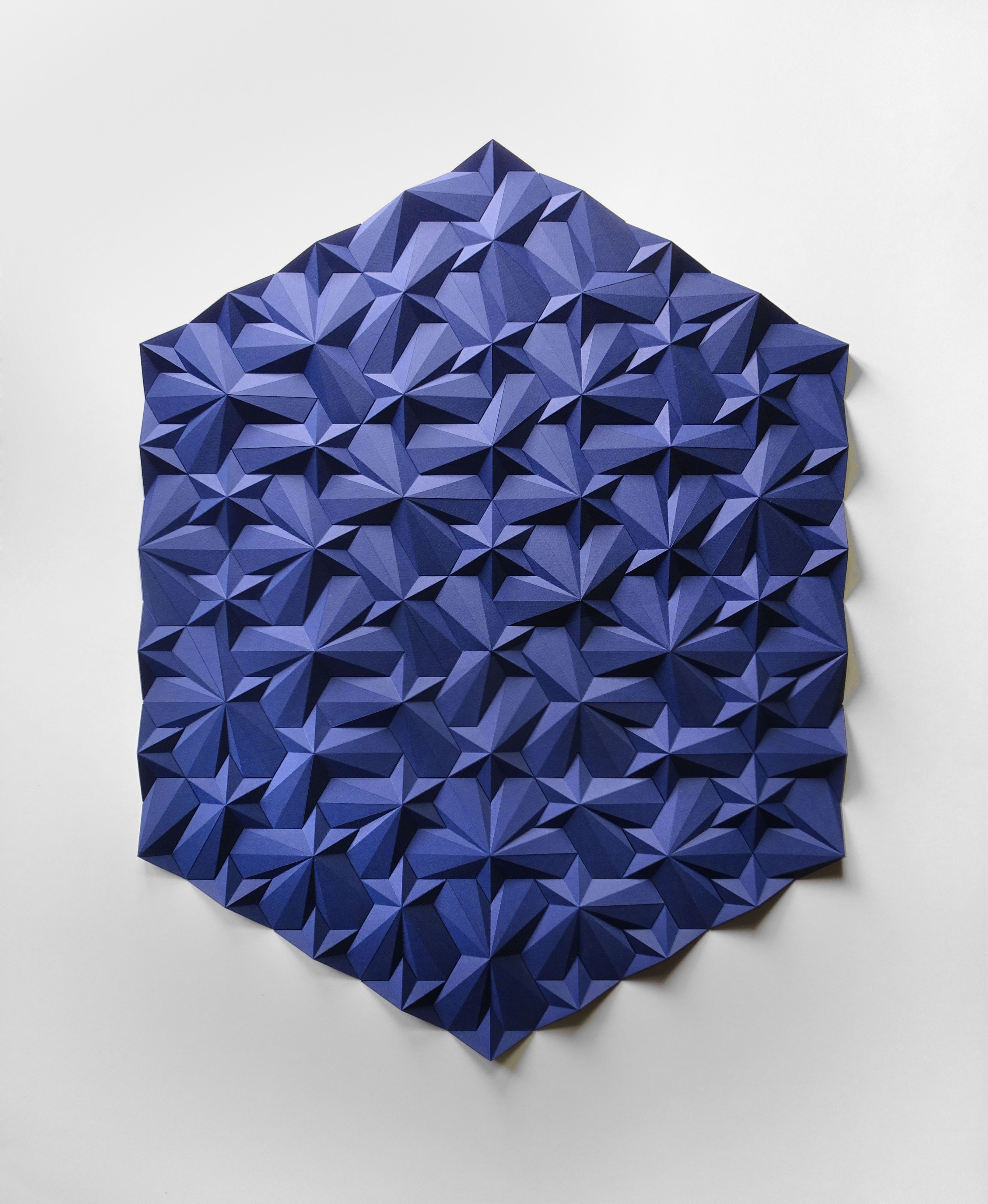 A blue paper sculpture on a white wall.