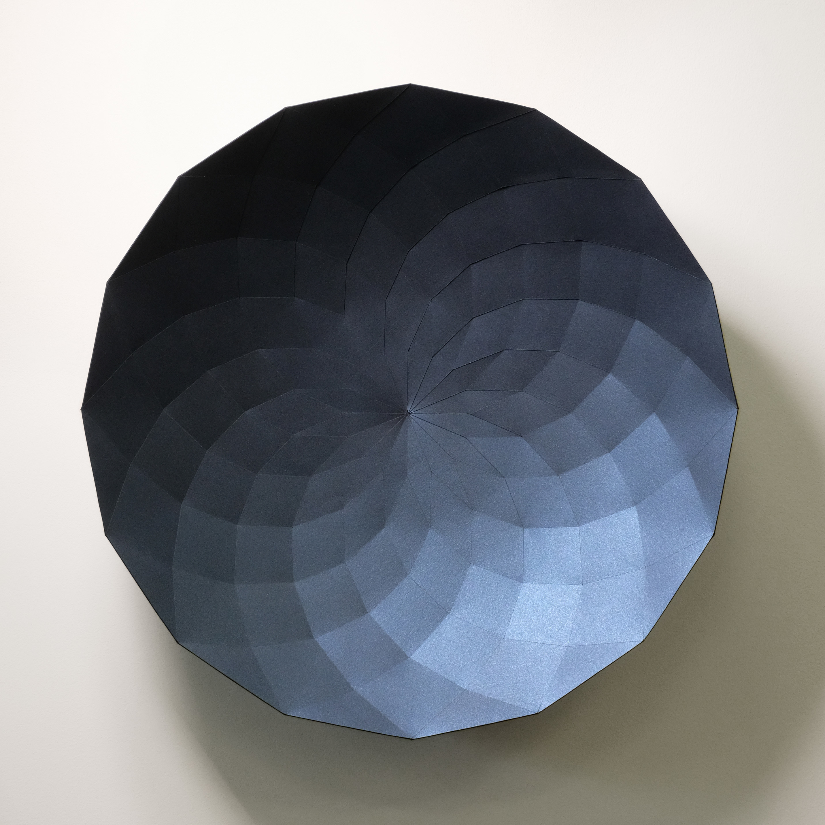 A black and blue paper sculpture on a white wall.