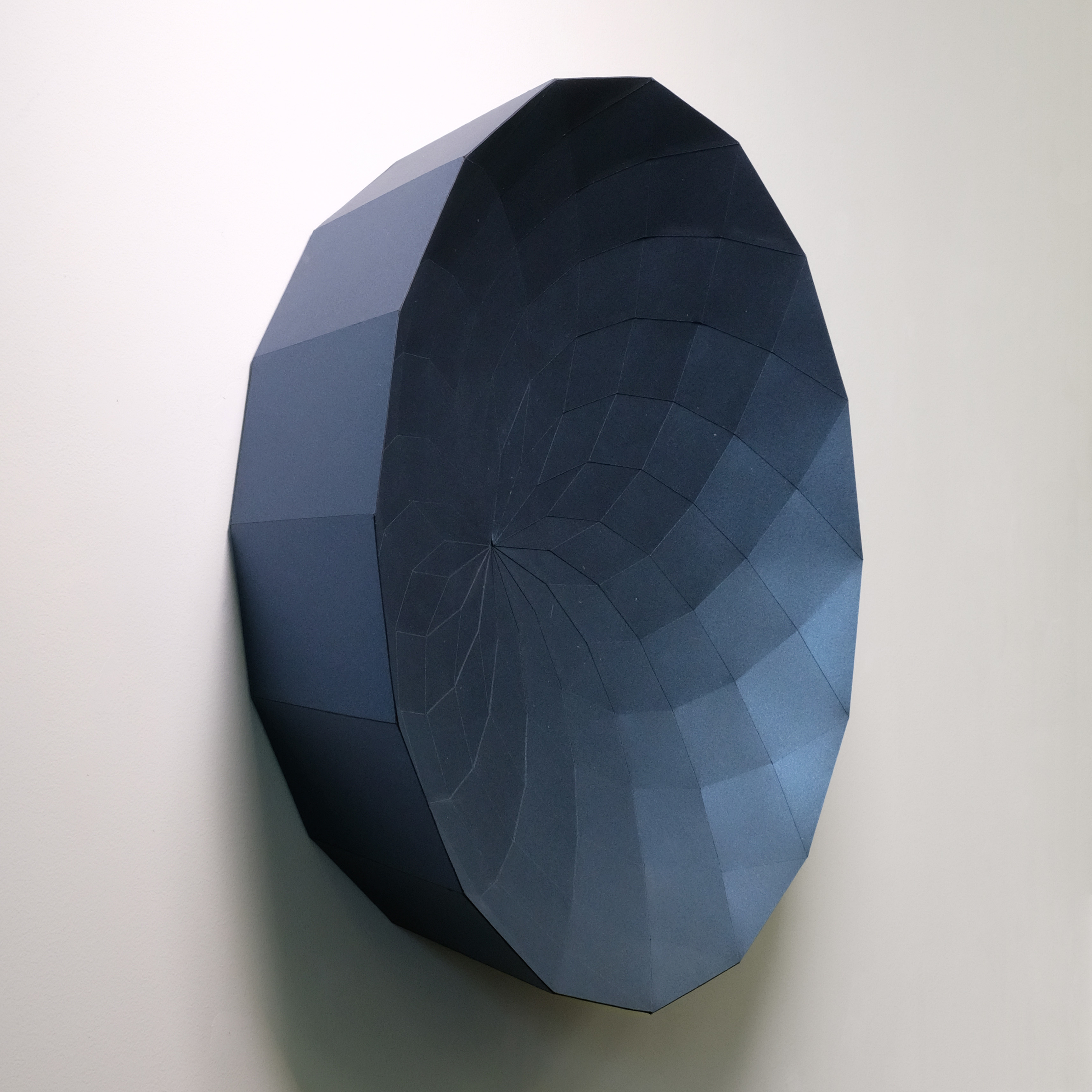 A black and blue paper sculpture on a white wall.