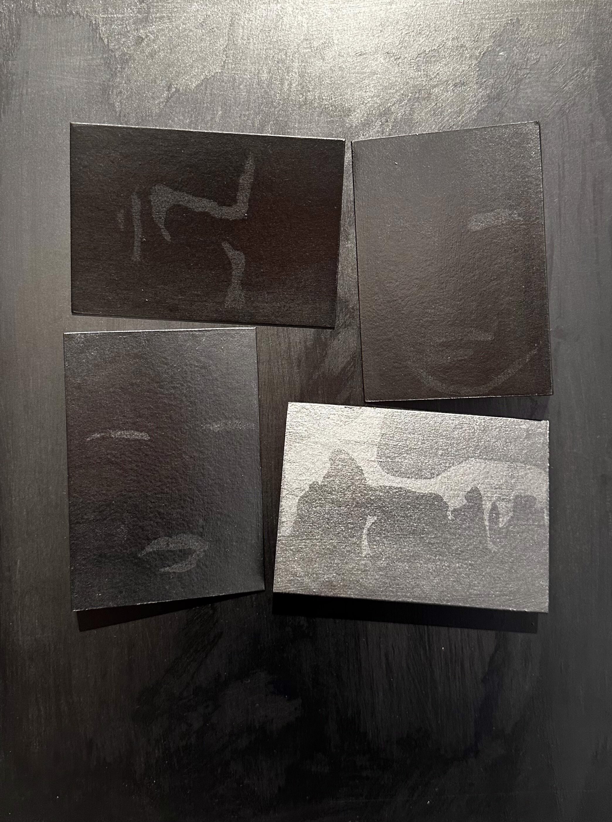 A set of four black and white paintings on a black surface.