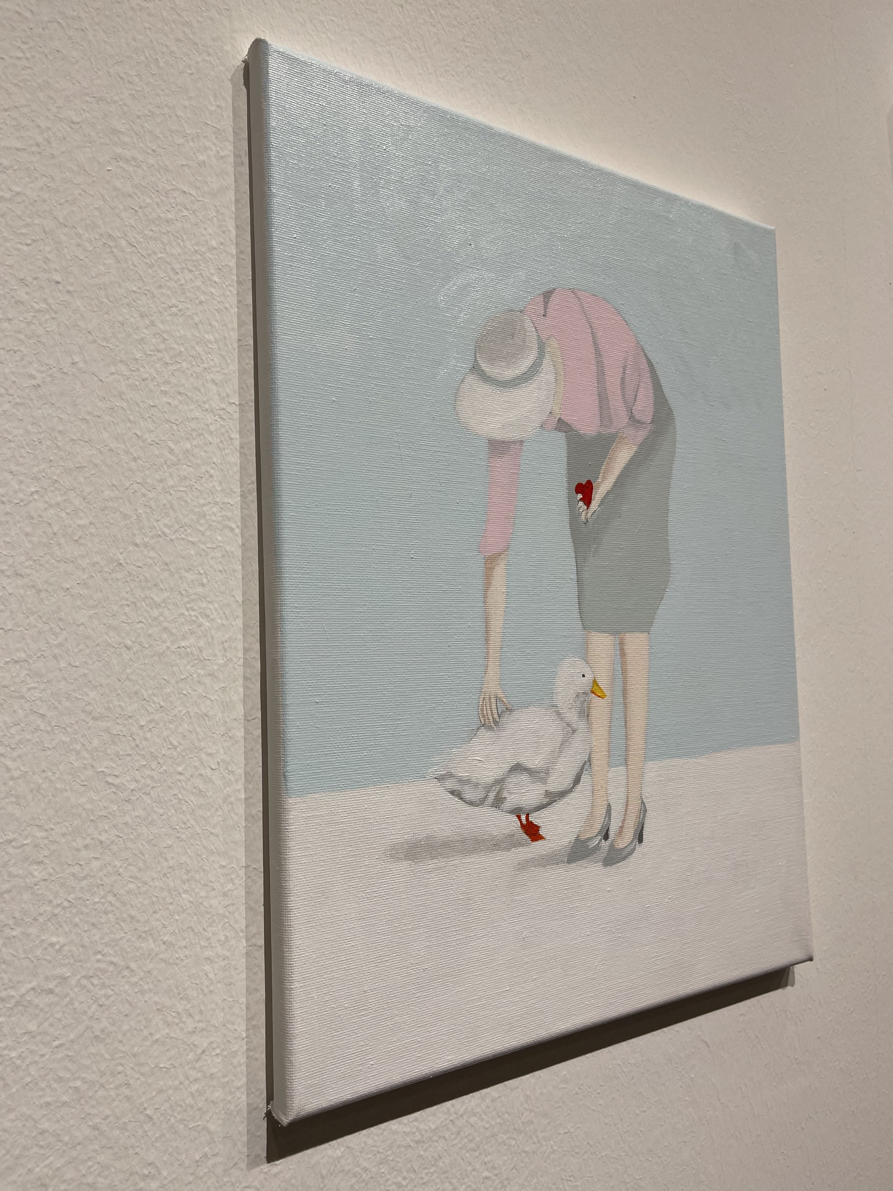 A painting of a woman feeding a duck with a heart.