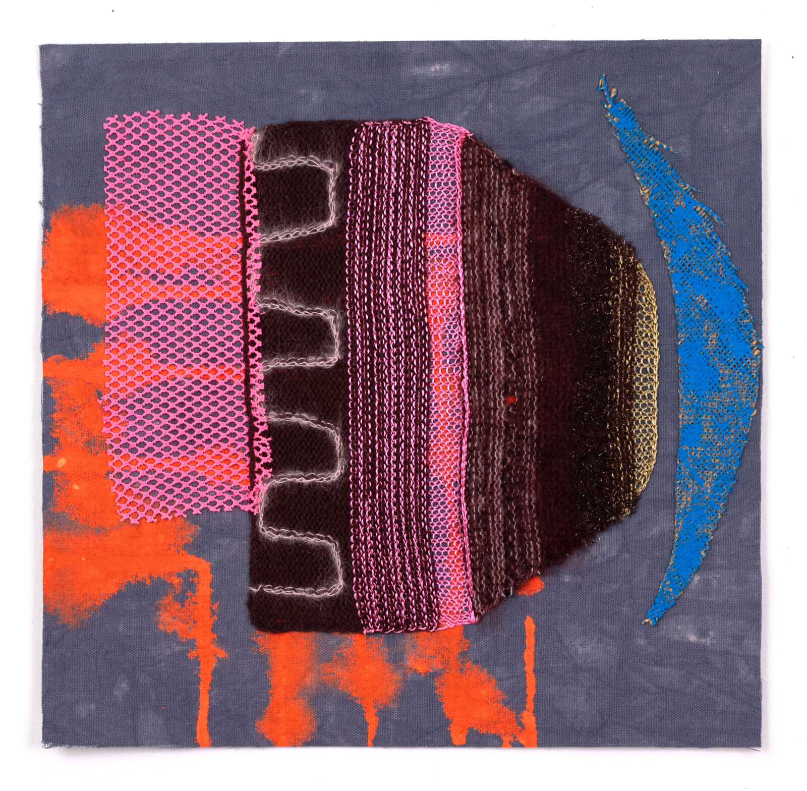 A mixed-media textile piece featuring a central brown knitted form with pink mesh, set against a grey background with orange and blue paint splatters.