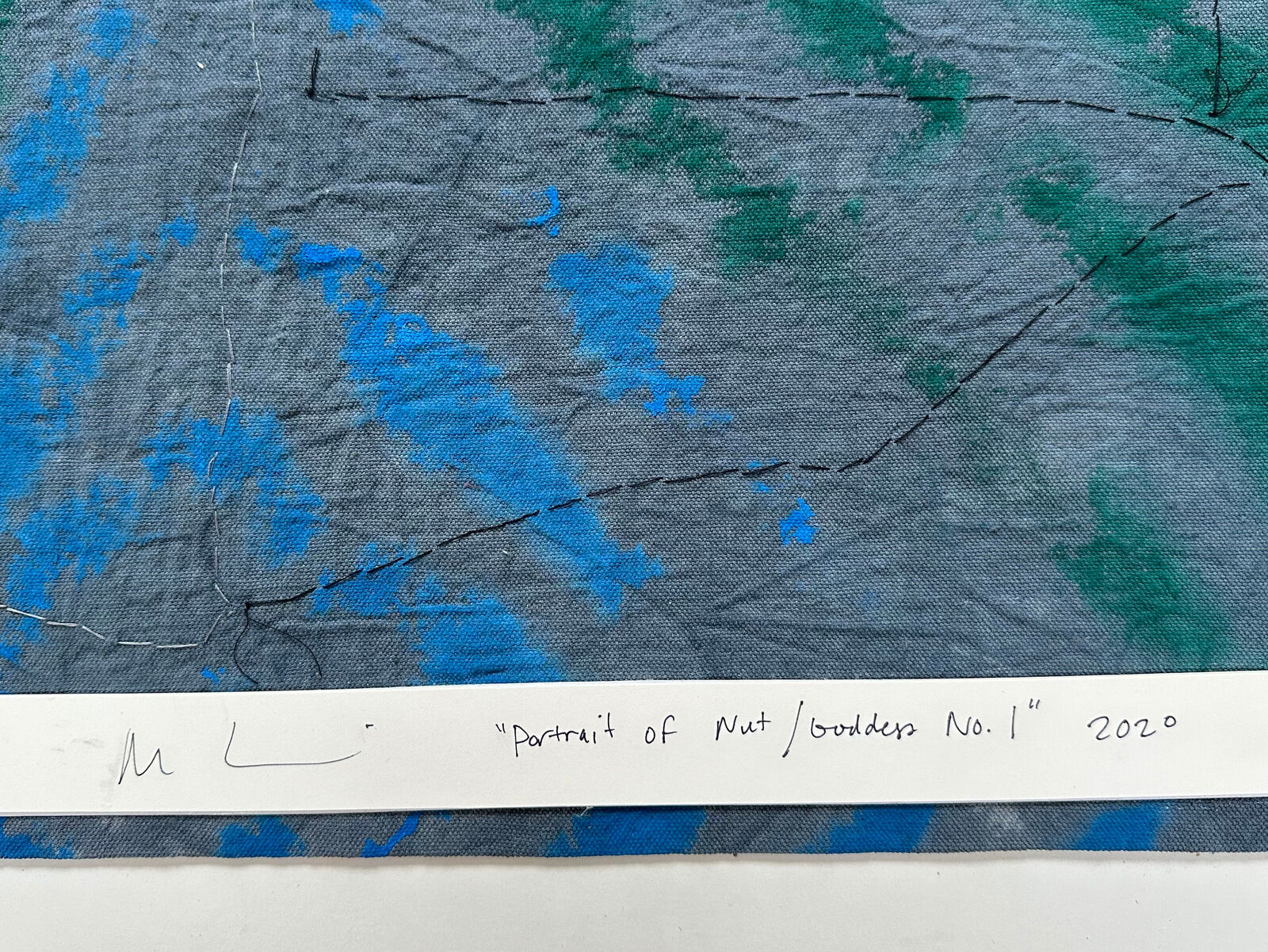 A textured textile artwork featuring a stylized helmet-like form against a tie-dye background.