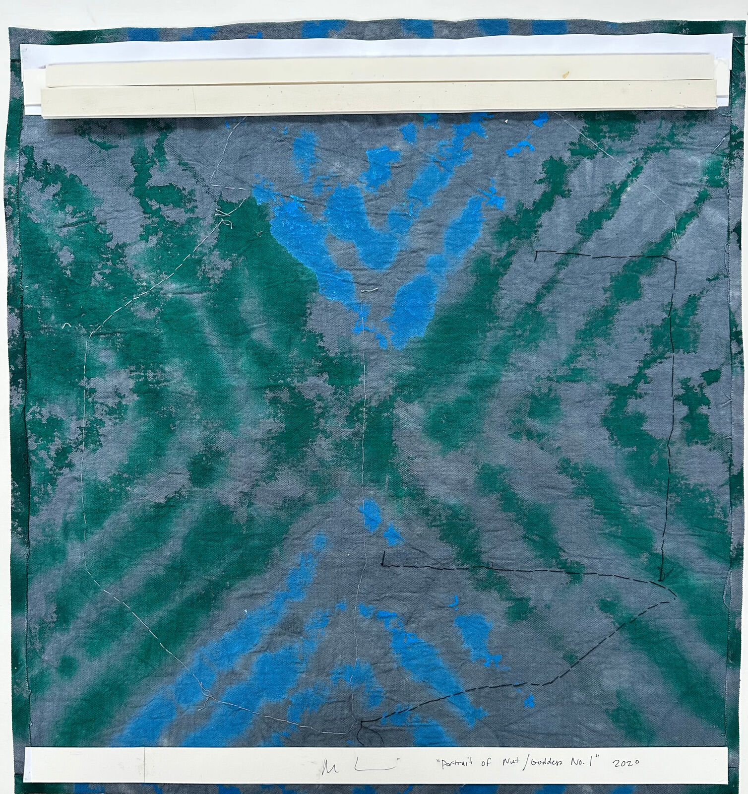 A textured textile artwork featuring a stylized helmet-like form against a tie-dye background.