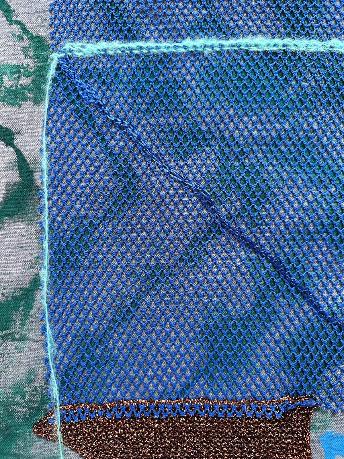 A textured textile artwork featuring a stylized helmet-like form against a tie-dye background.