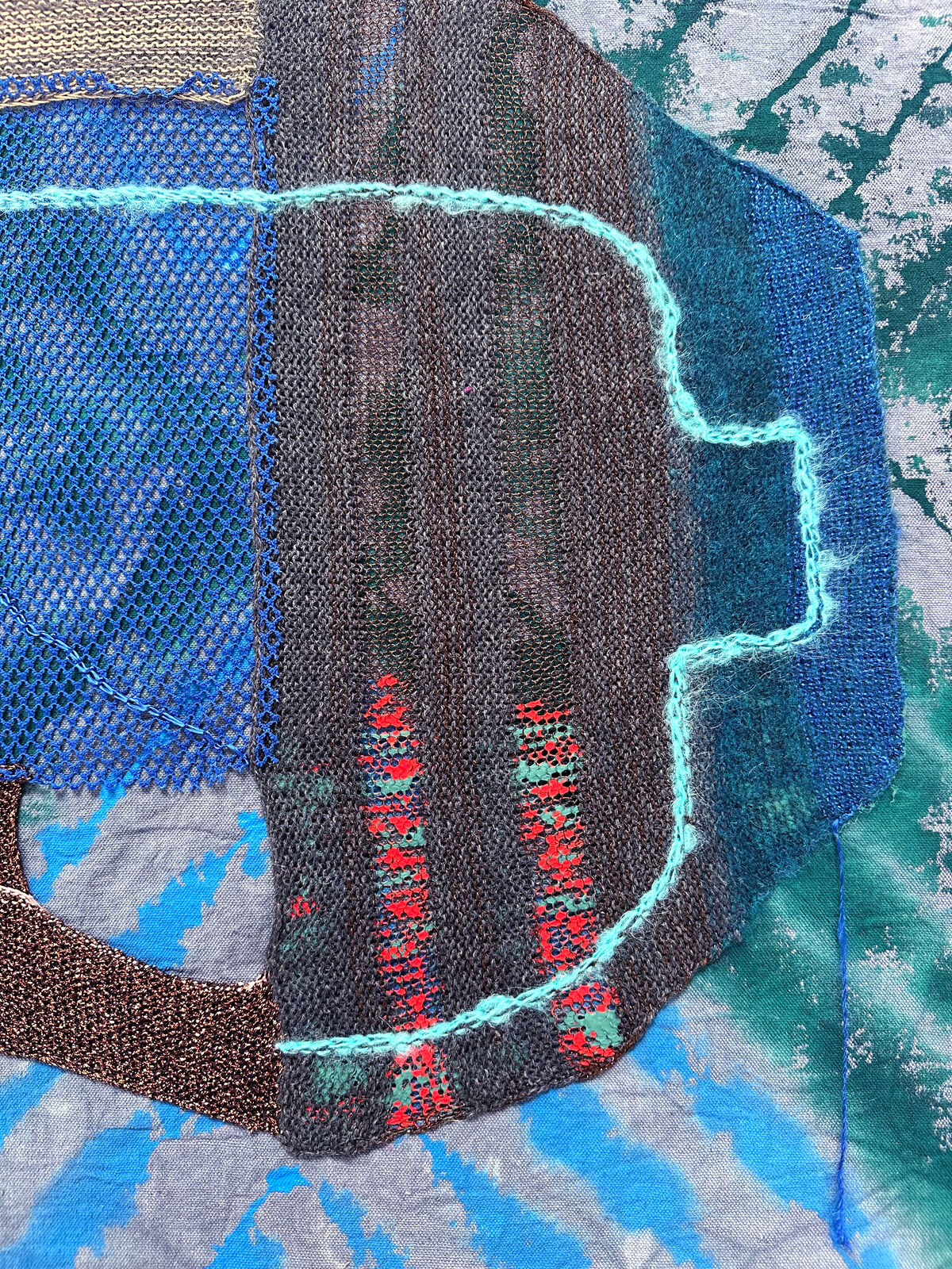A textured textile artwork featuring a stylized helmet-like form against a tie-dye background.