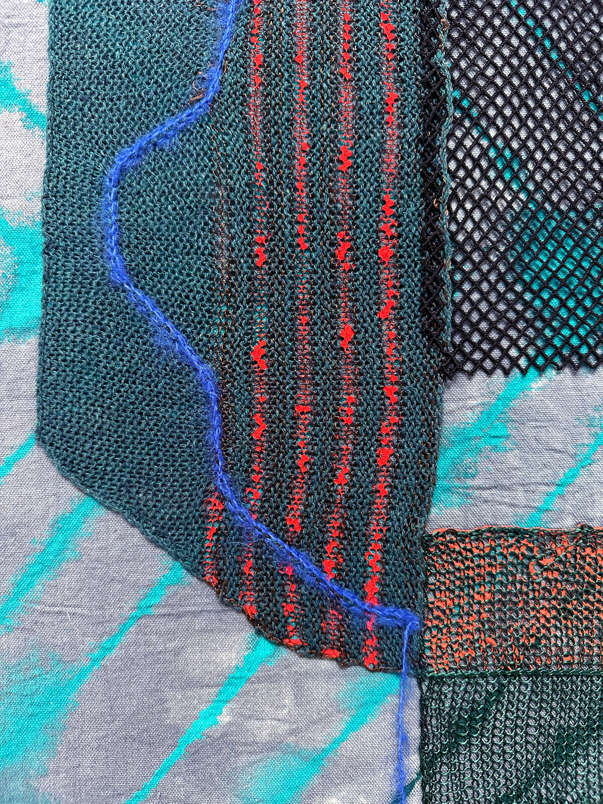 A textile collage featuring layered fabrics and abstract shapes.