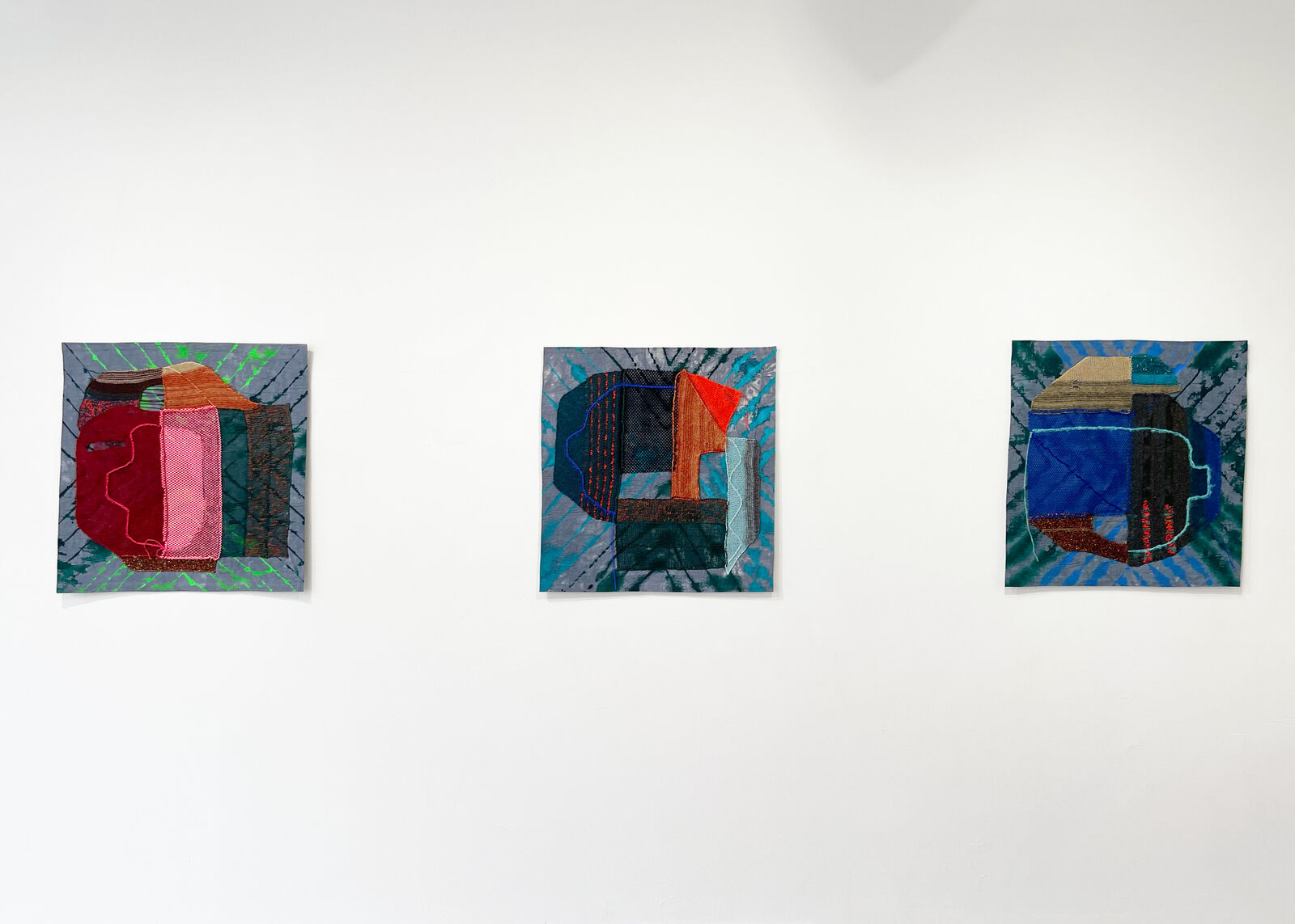 A textured textile artwork featuring a stylized face with vibrant colors and mixed media elements.