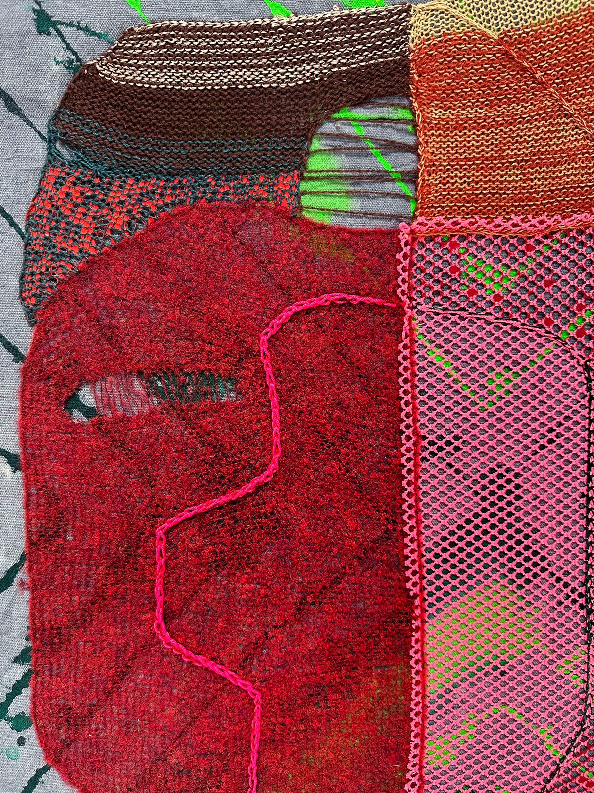 A textured textile artwork featuring a stylized face with vibrant colors and mixed media elements.