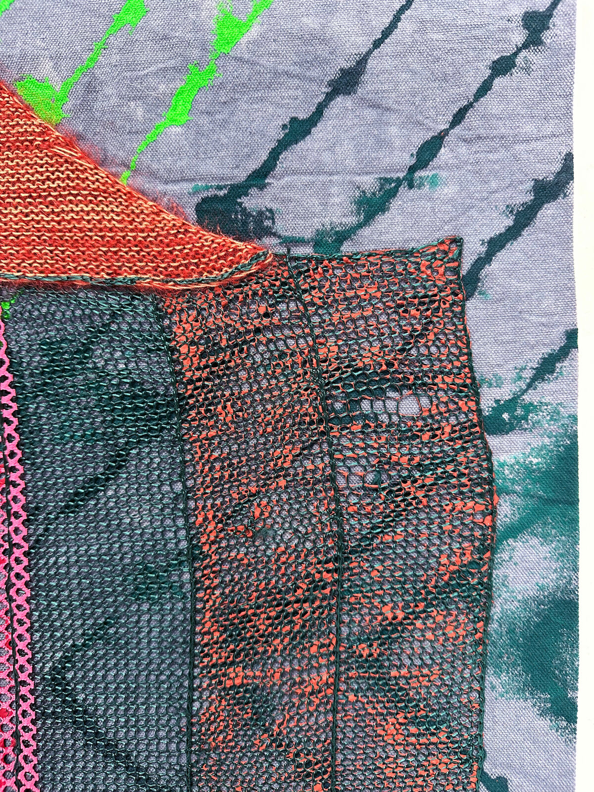 A textured textile artwork featuring a stylized face with vibrant colors and mixed media elements.