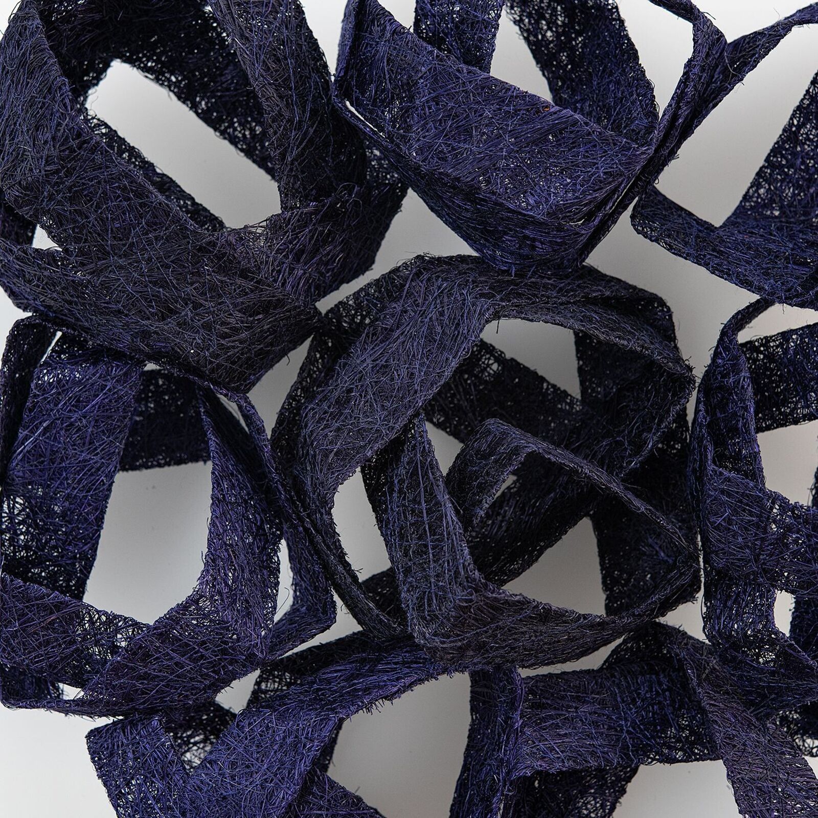 A framed textile sculpture featuring interwoven dark blue ribbons.