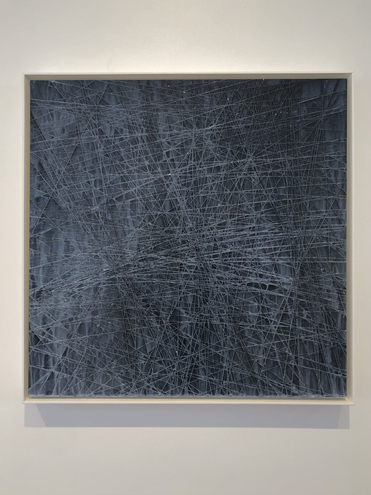 "A monochromatic abstract composition featuring a dense web of intersecting lines on a dark background."