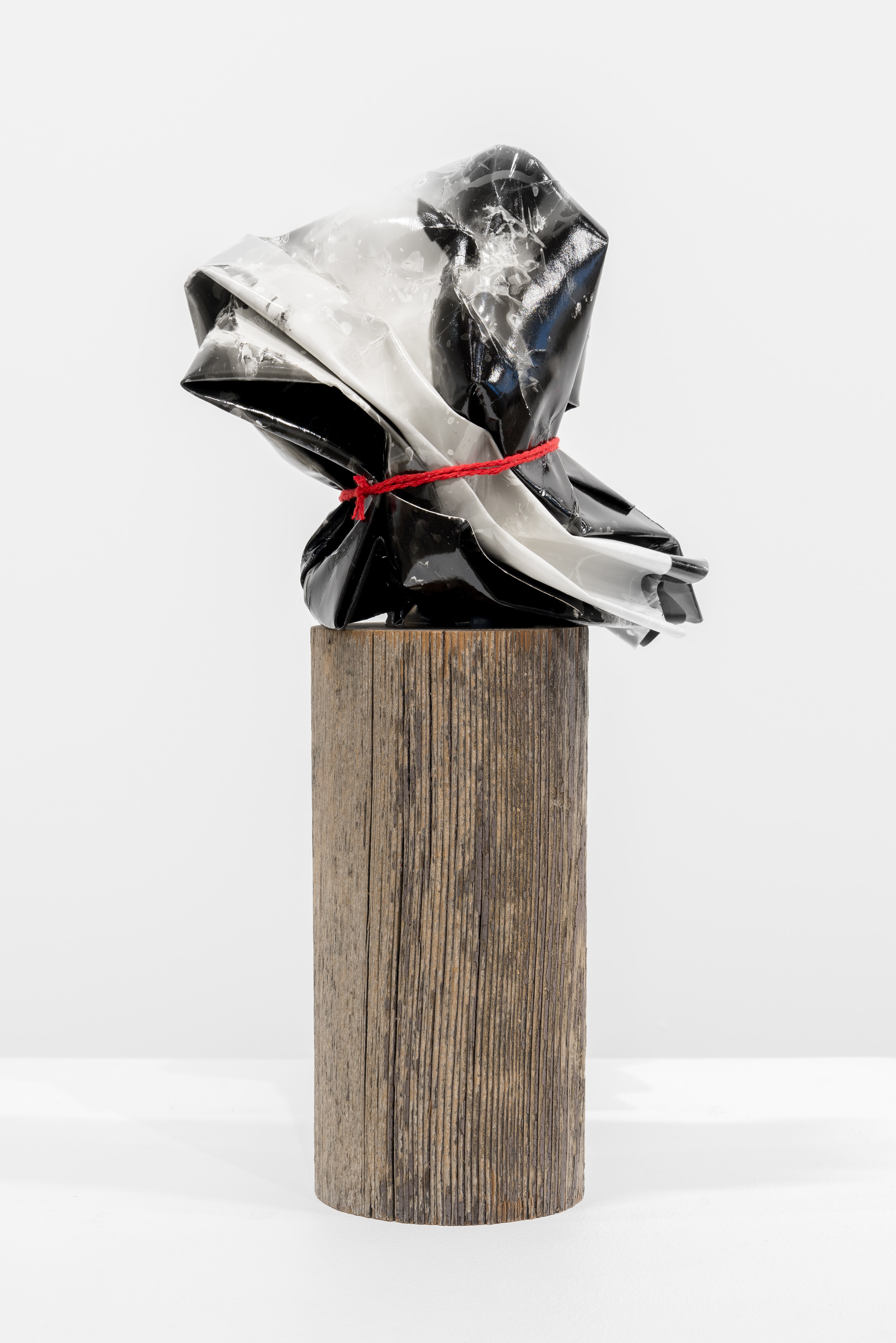 A black and white sculpture on a wooden pedestal.
