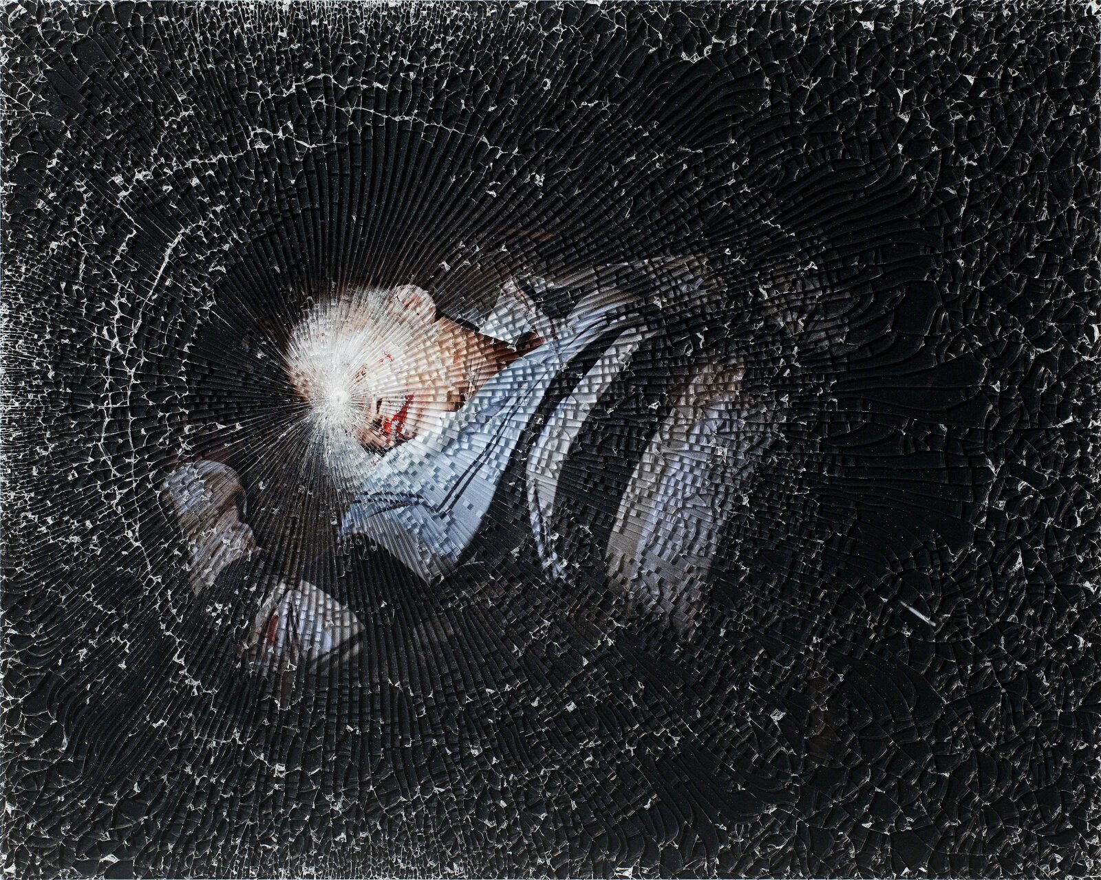 A broken glass window with a person laying on the ground.