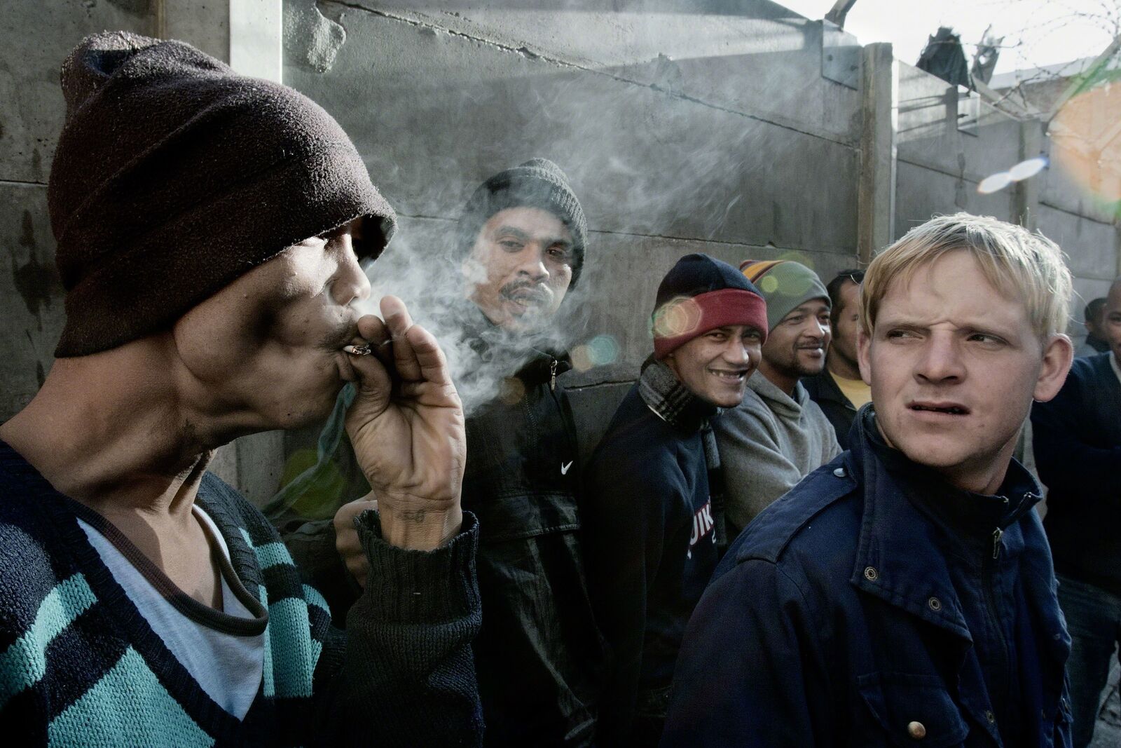 A group of men standing next to each other smoking a cigarette.