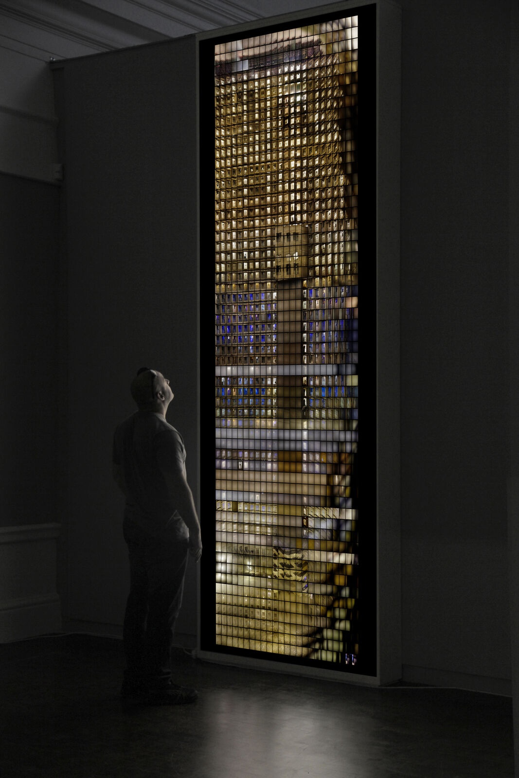 A man standing in front of a large window in a dark room.