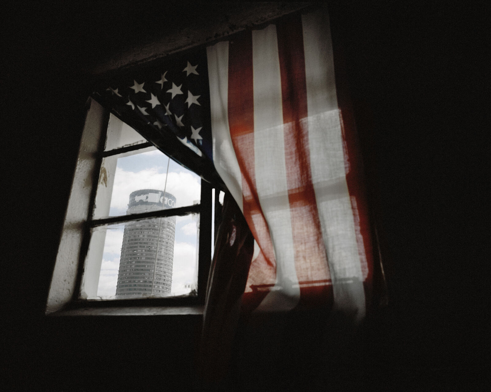 A window with an American flag hanging from it's side.