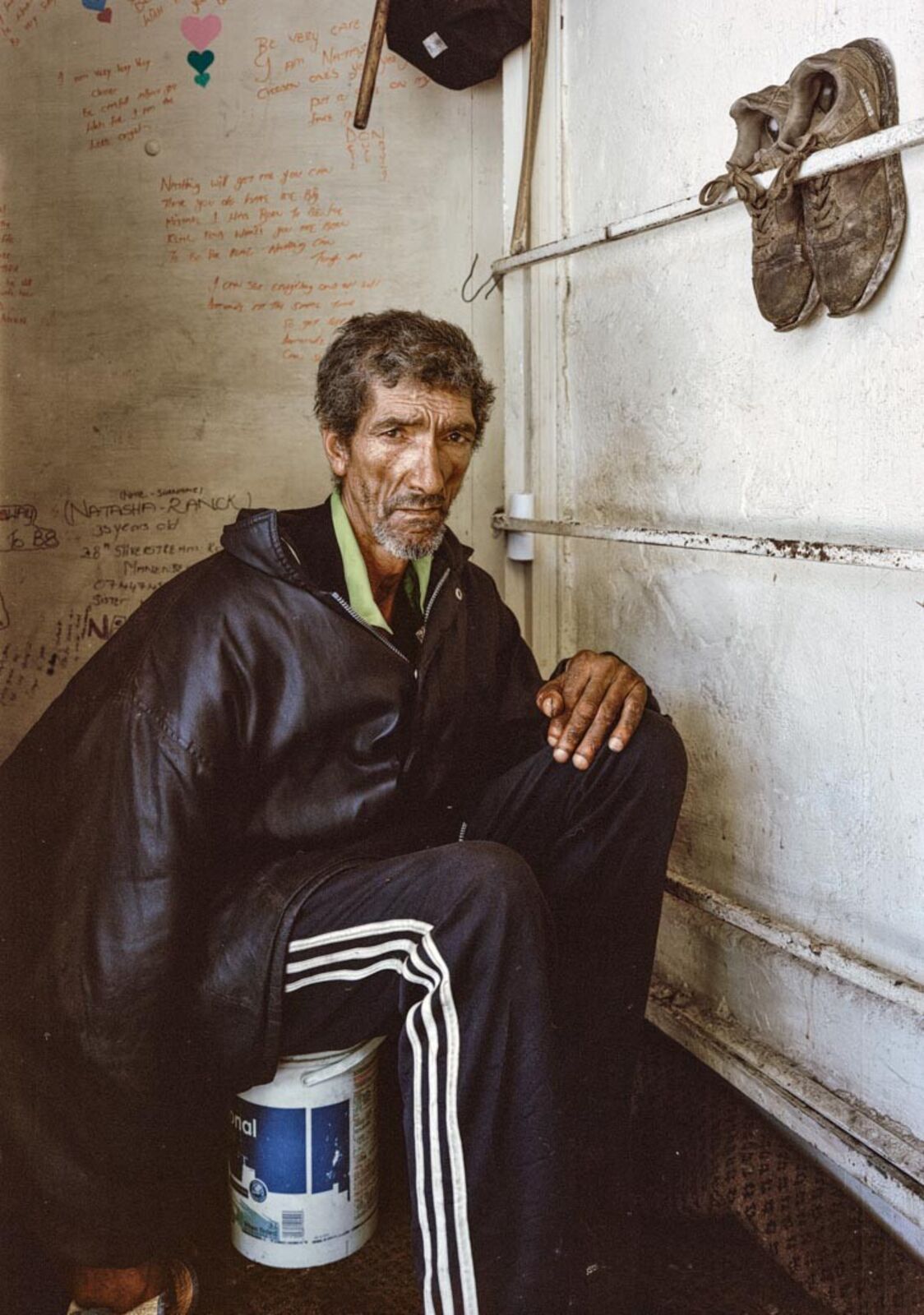 A man sitting on the floor in a room with a bucket of paint.