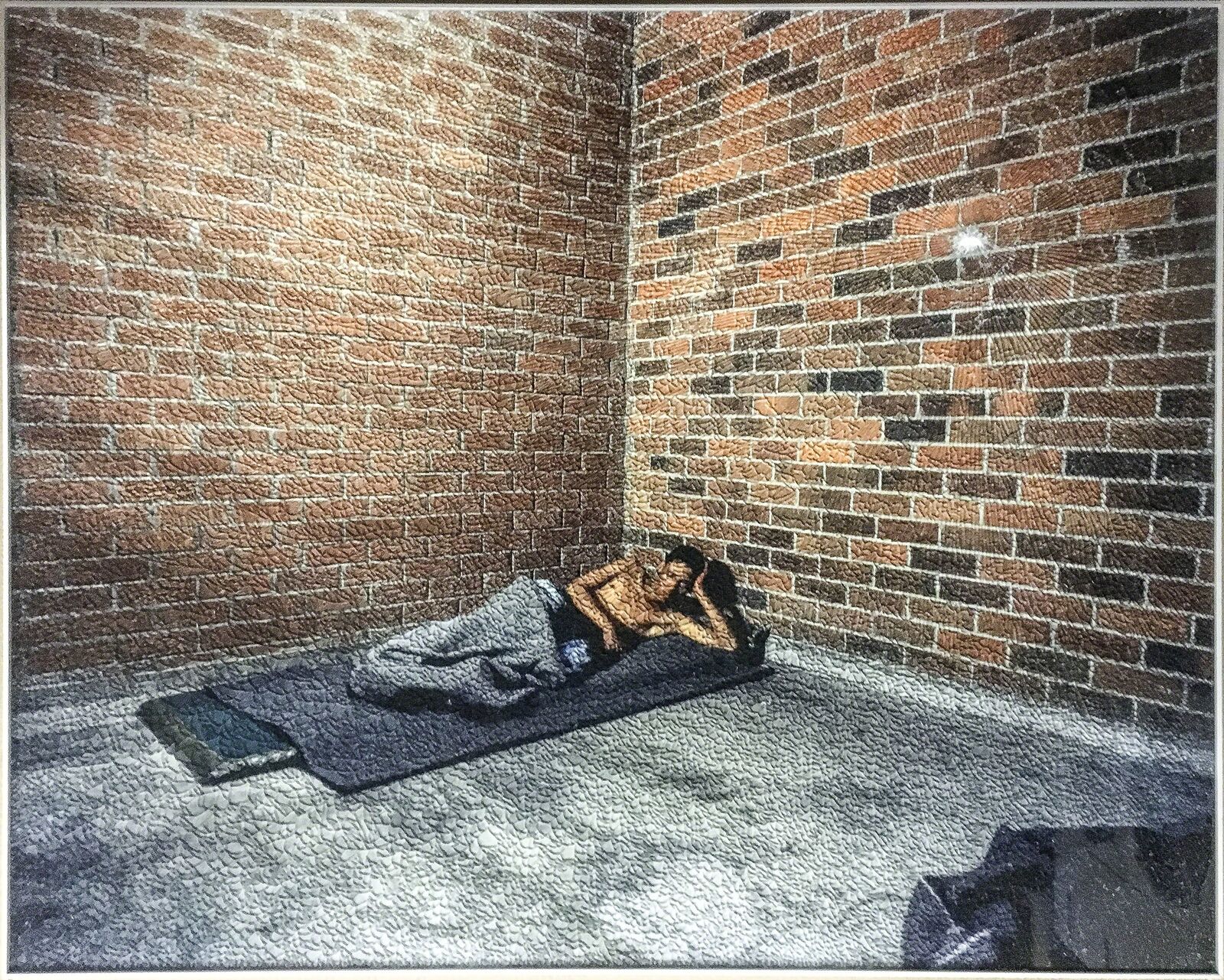 A person laying on a blanket in a room with a brick wall.