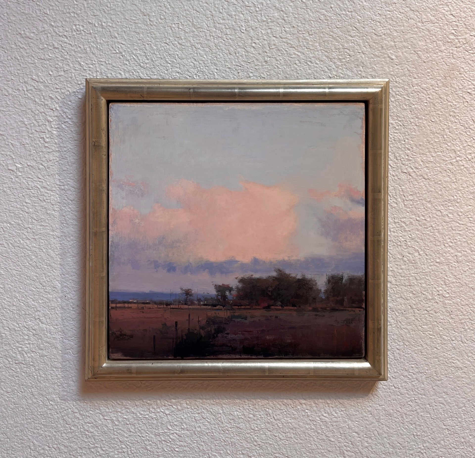 A painting of a field with trees in the distance.