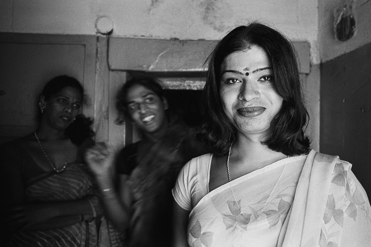 A woman in a white sari standing in front of a group of people.