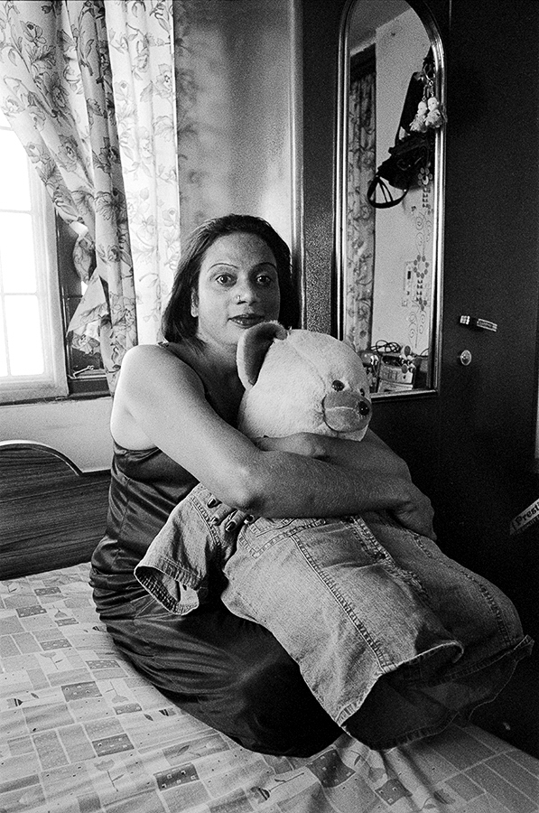 A woman sitting on a bed holding a teddy bear.