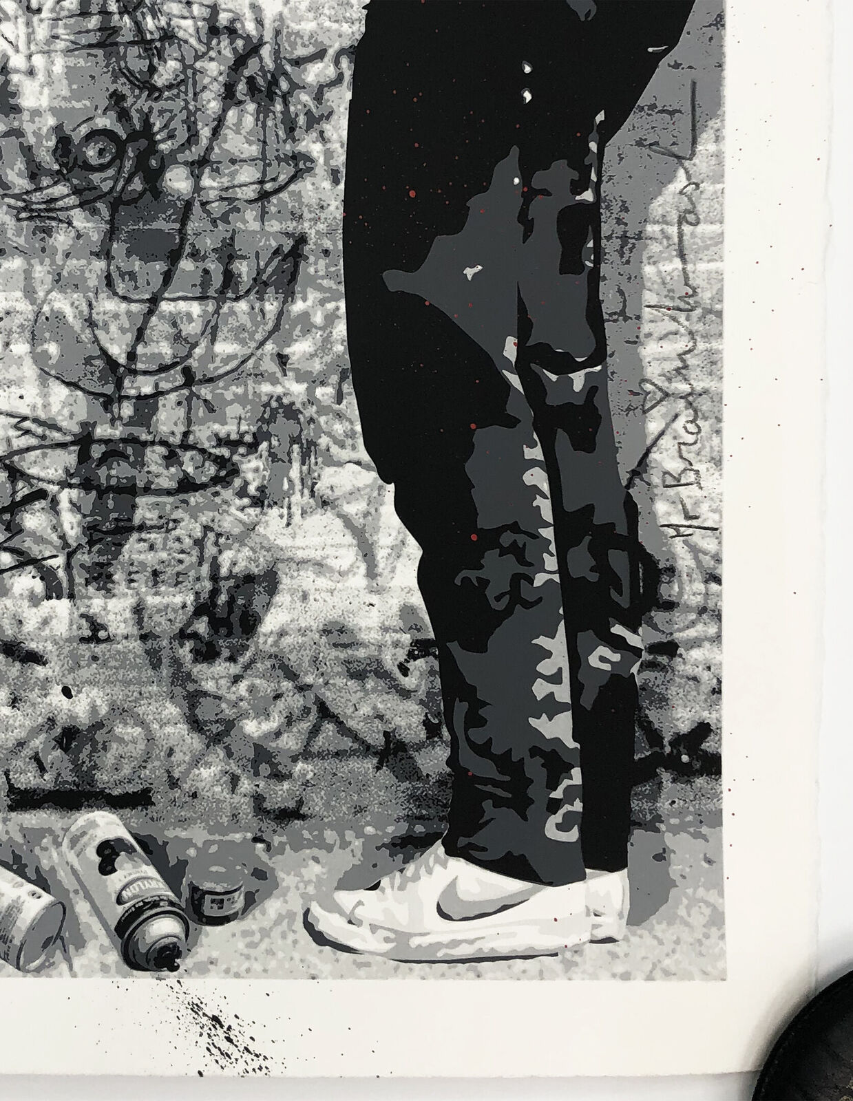 A black and white picture of a man standing in front of a wall with graffiti.