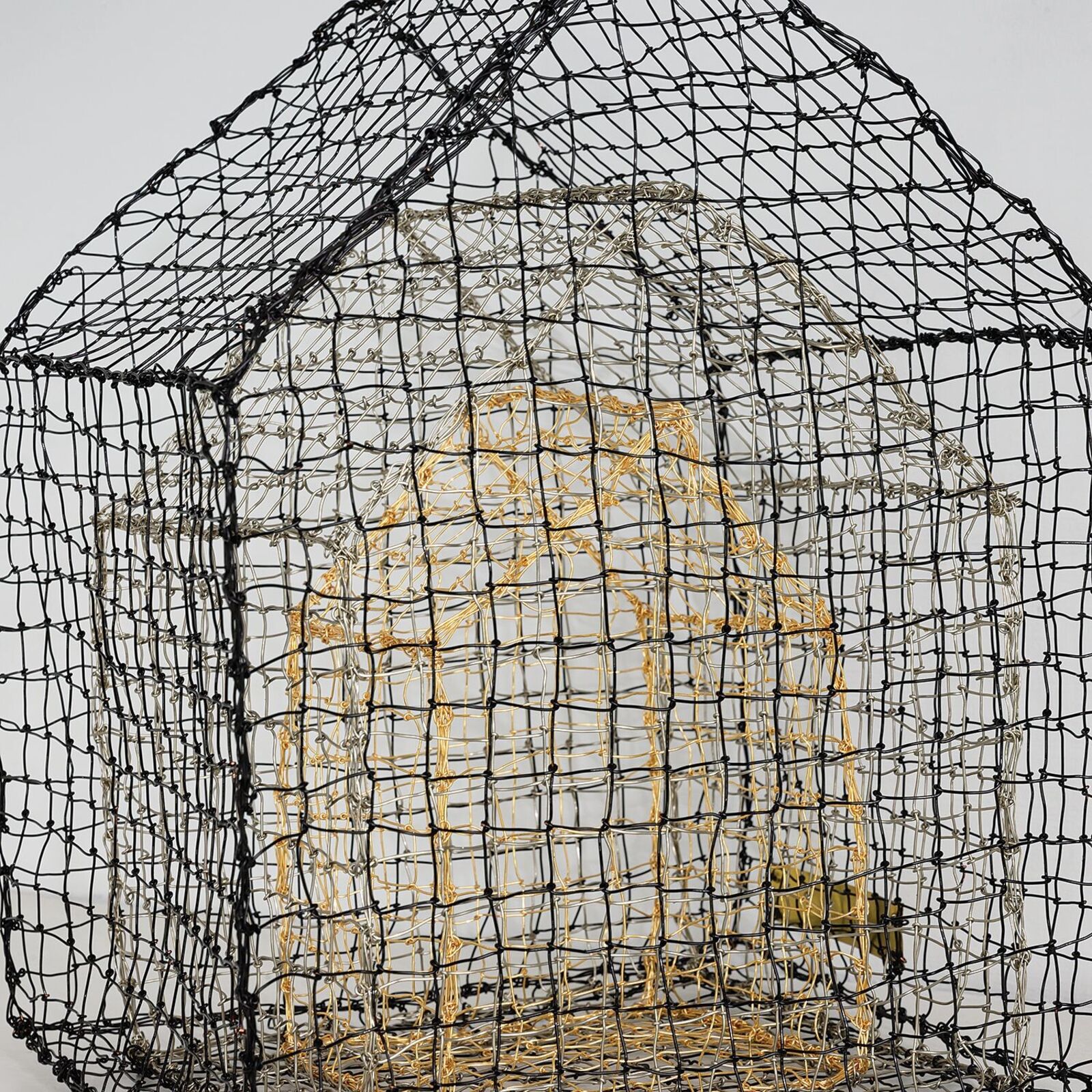 A wireframe house sculpture with a golden interior structure.