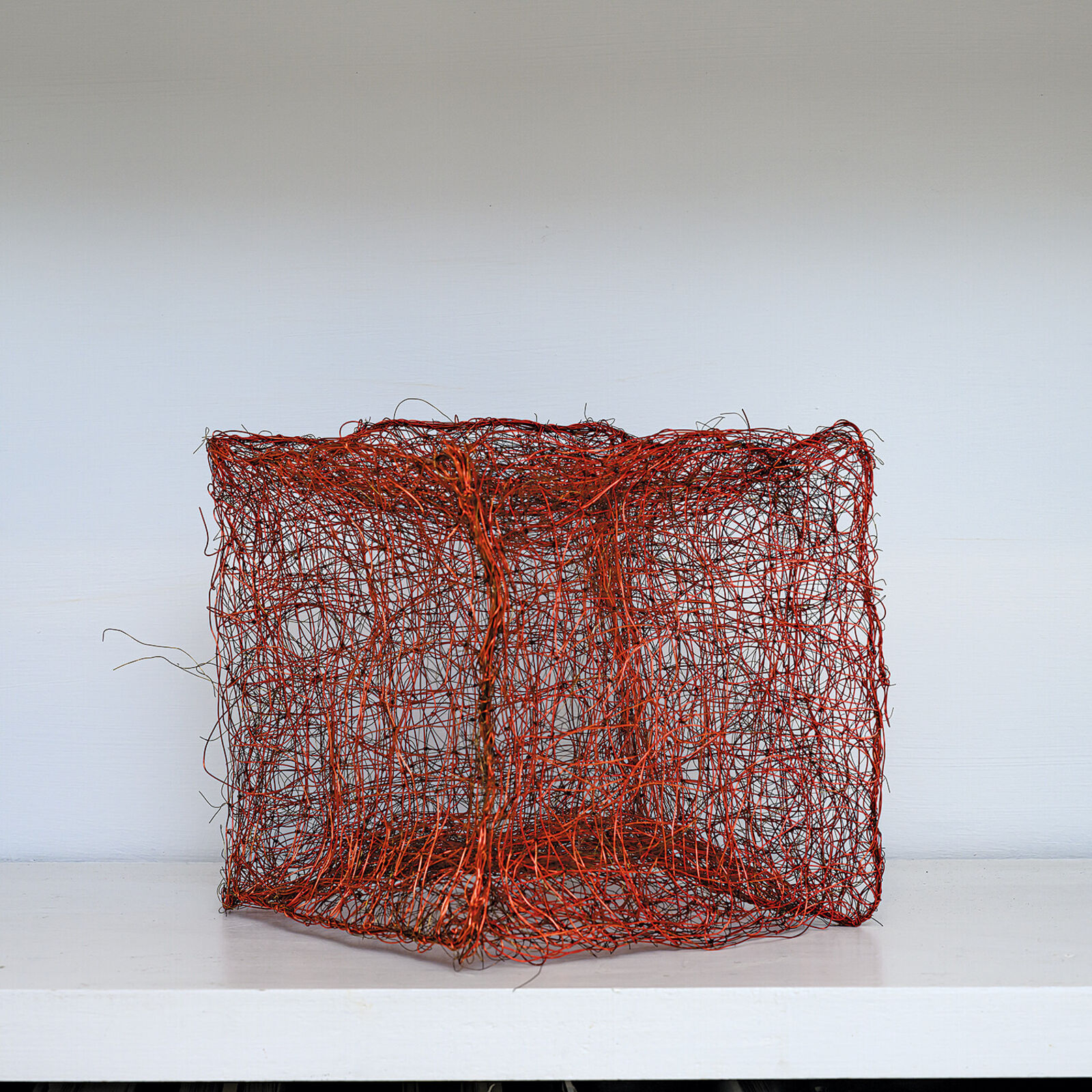 "A tangled, red wire sculpture resembling a chaotic cube."
