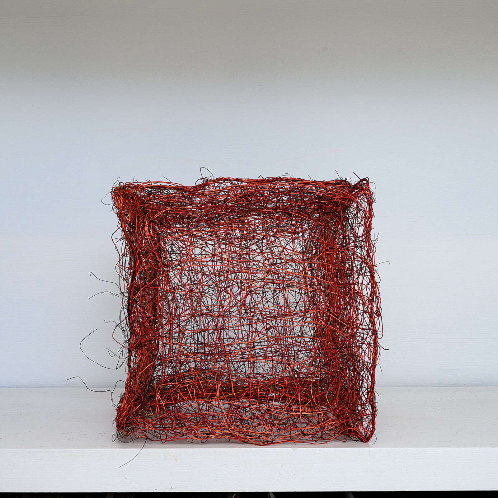 "A tangled, red wire sculpture resembling a chaotic cube."