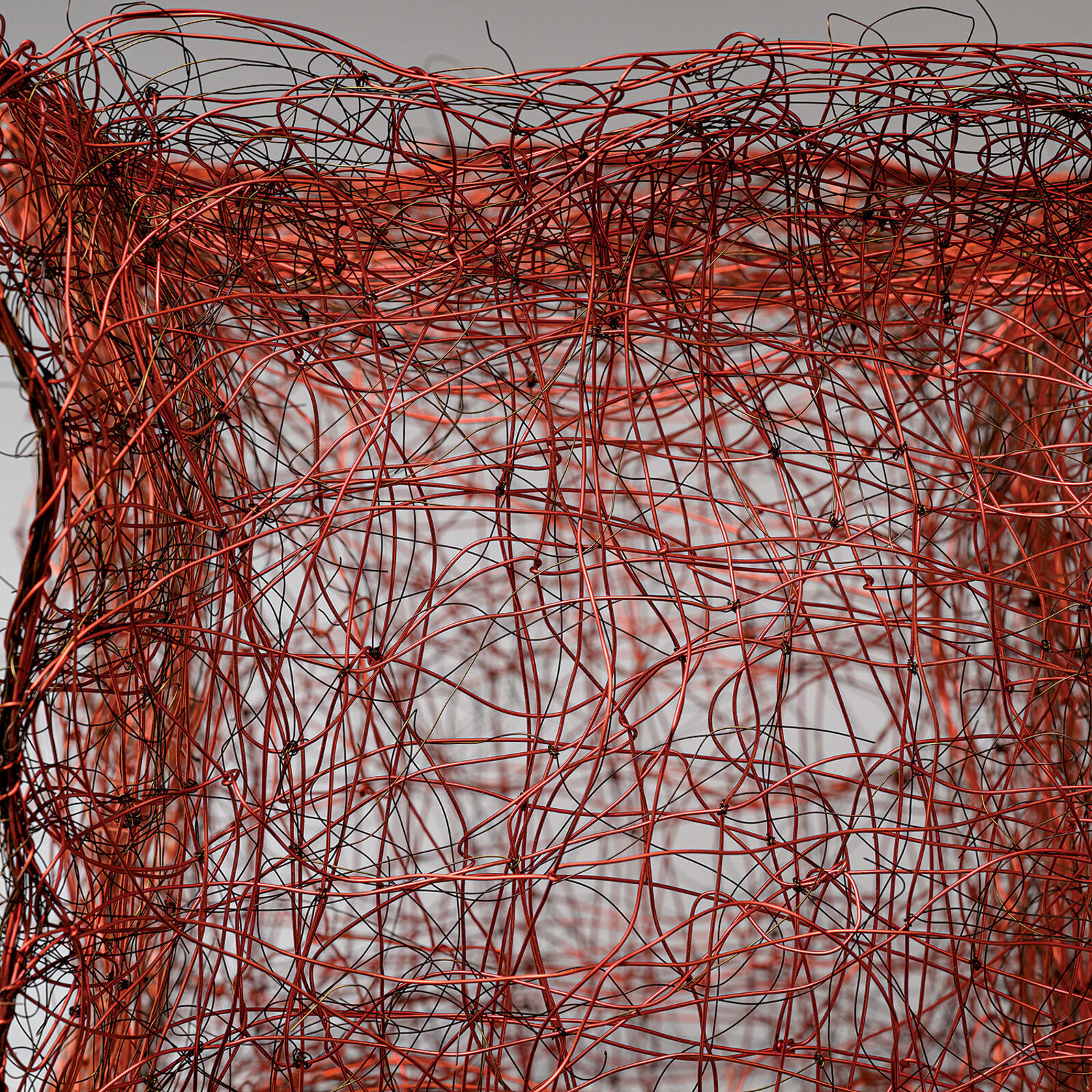 "A tangled, red wire sculpture resembling a chaotic cube."