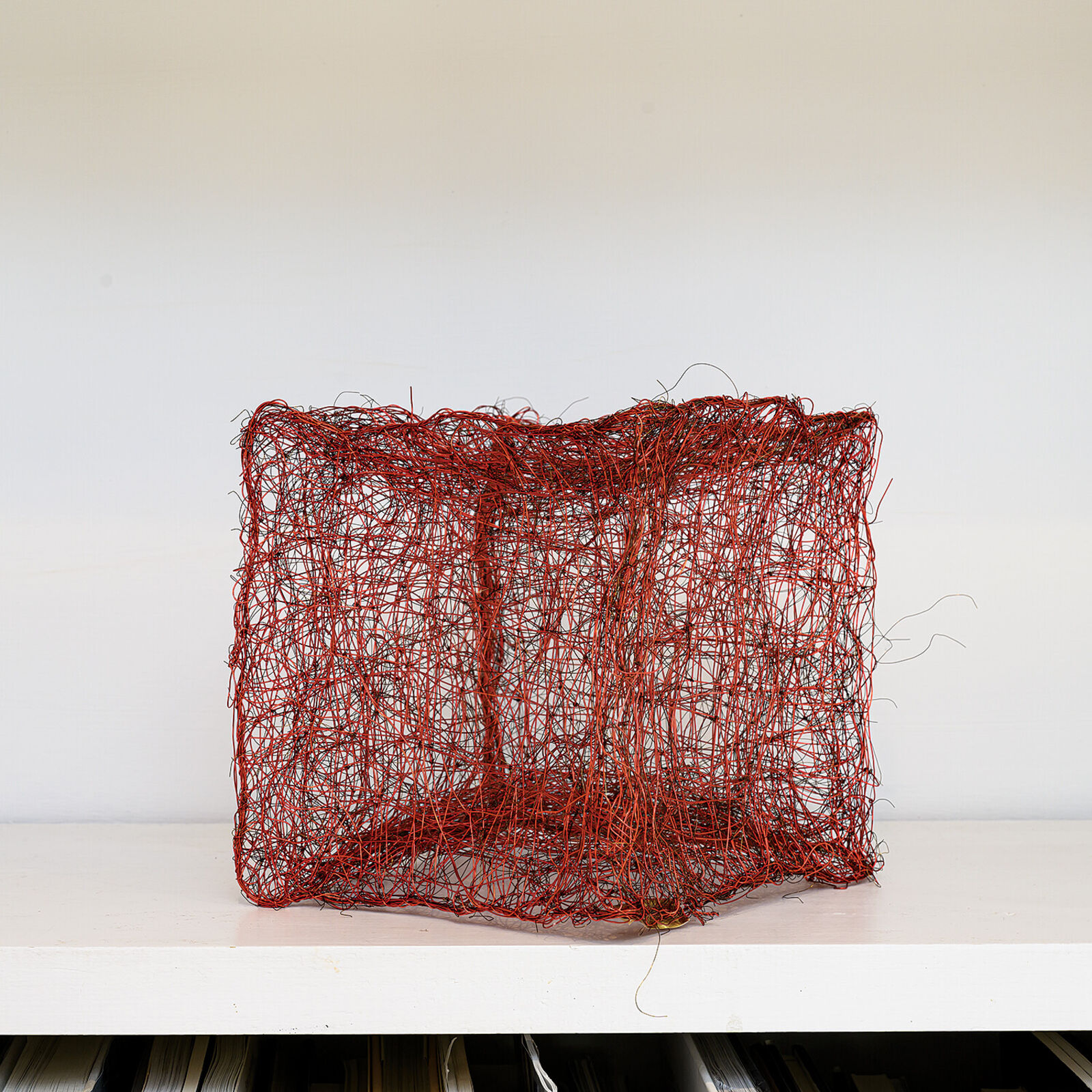 "A tangled, red wire sculpture resembling a chaotic cube."