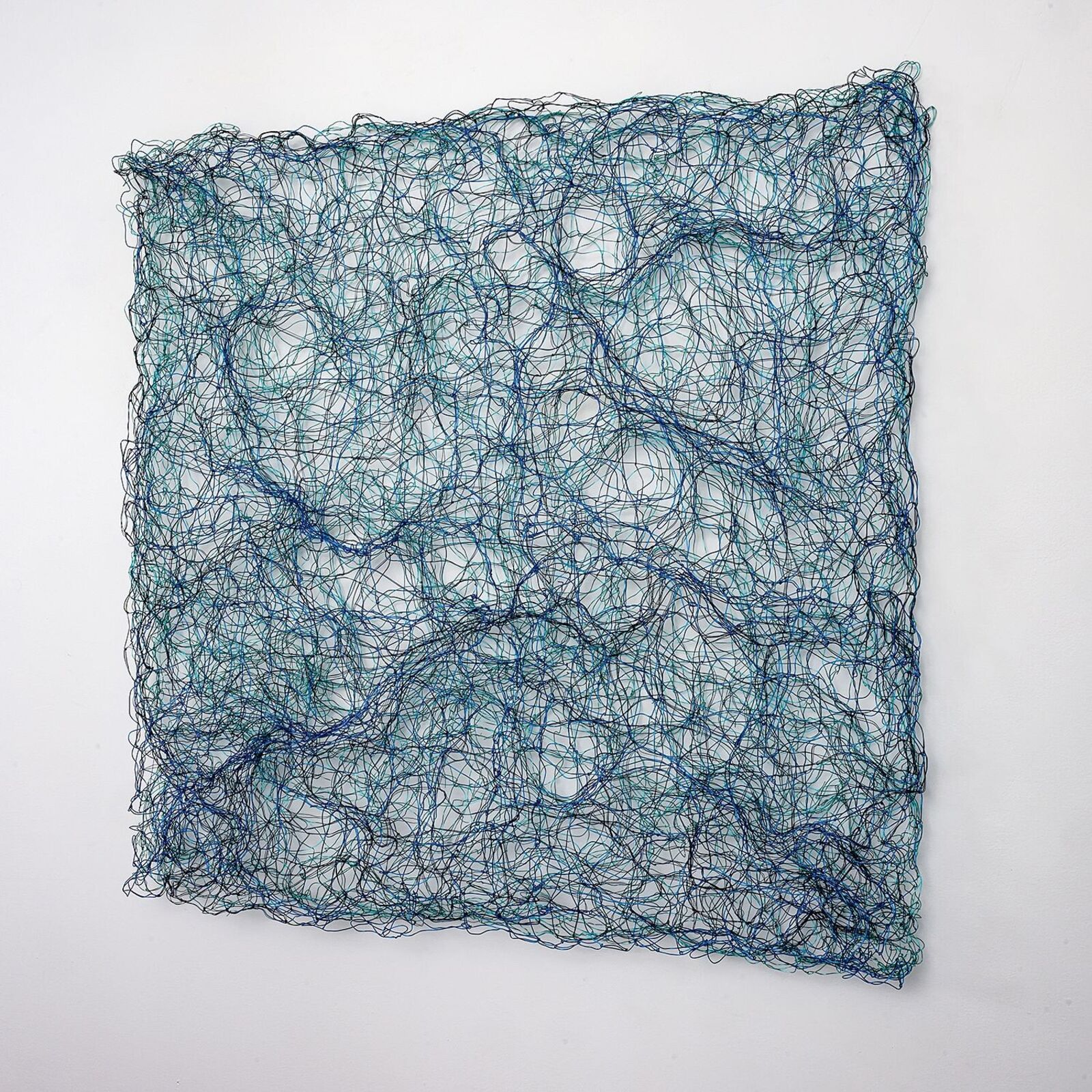 A square wire sculpture with a tangled, organic pattern in shades of blue and black against a white background.