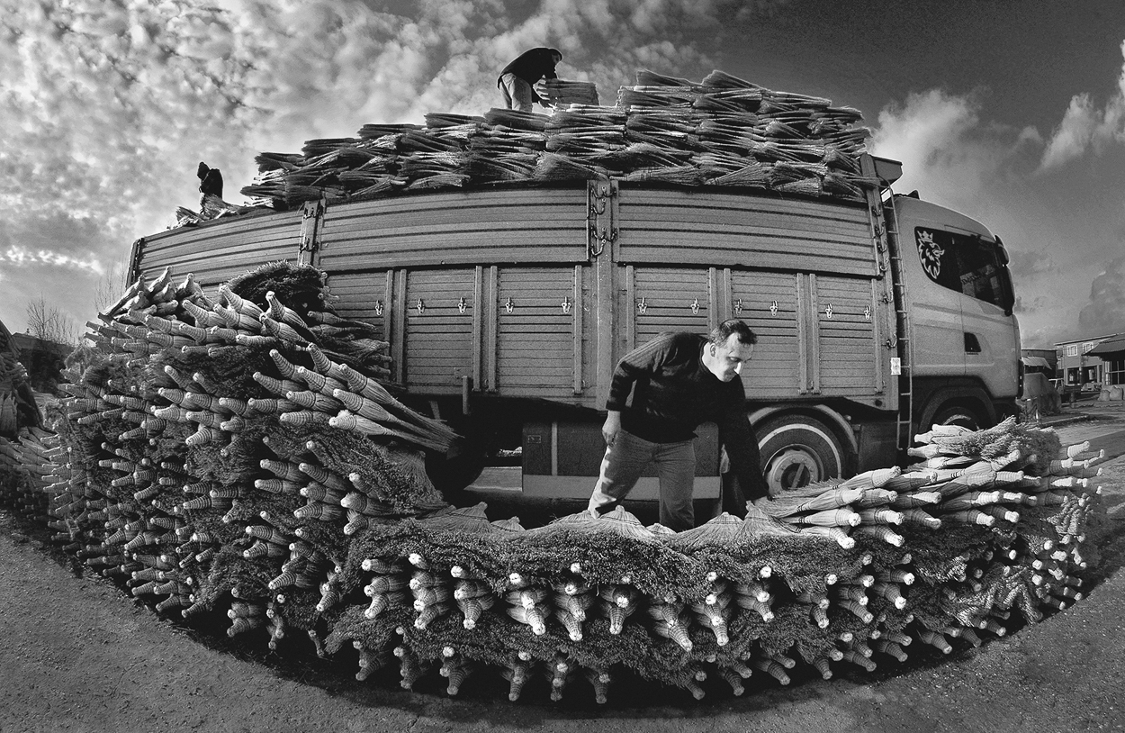 A man standing next to a truck loaded with corn on the back of it.