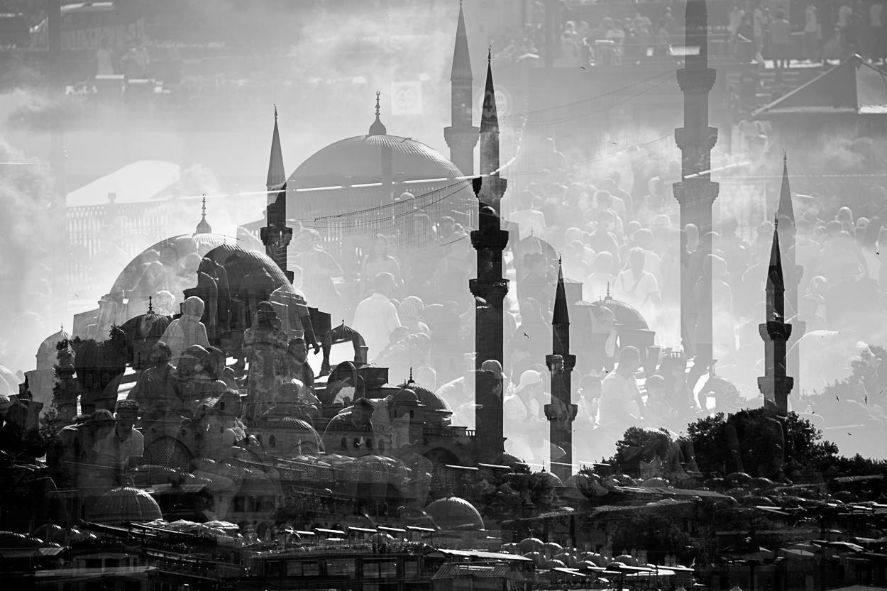 A black and white photo of a large group of people in front of a mosque.