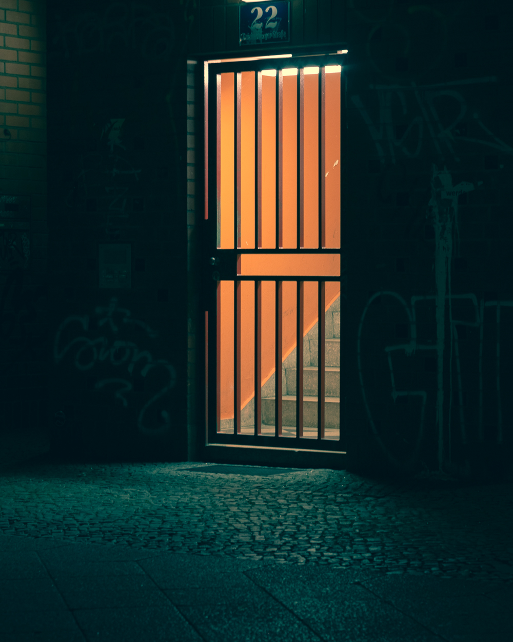 A door in a dark room with graffiti on the walls.