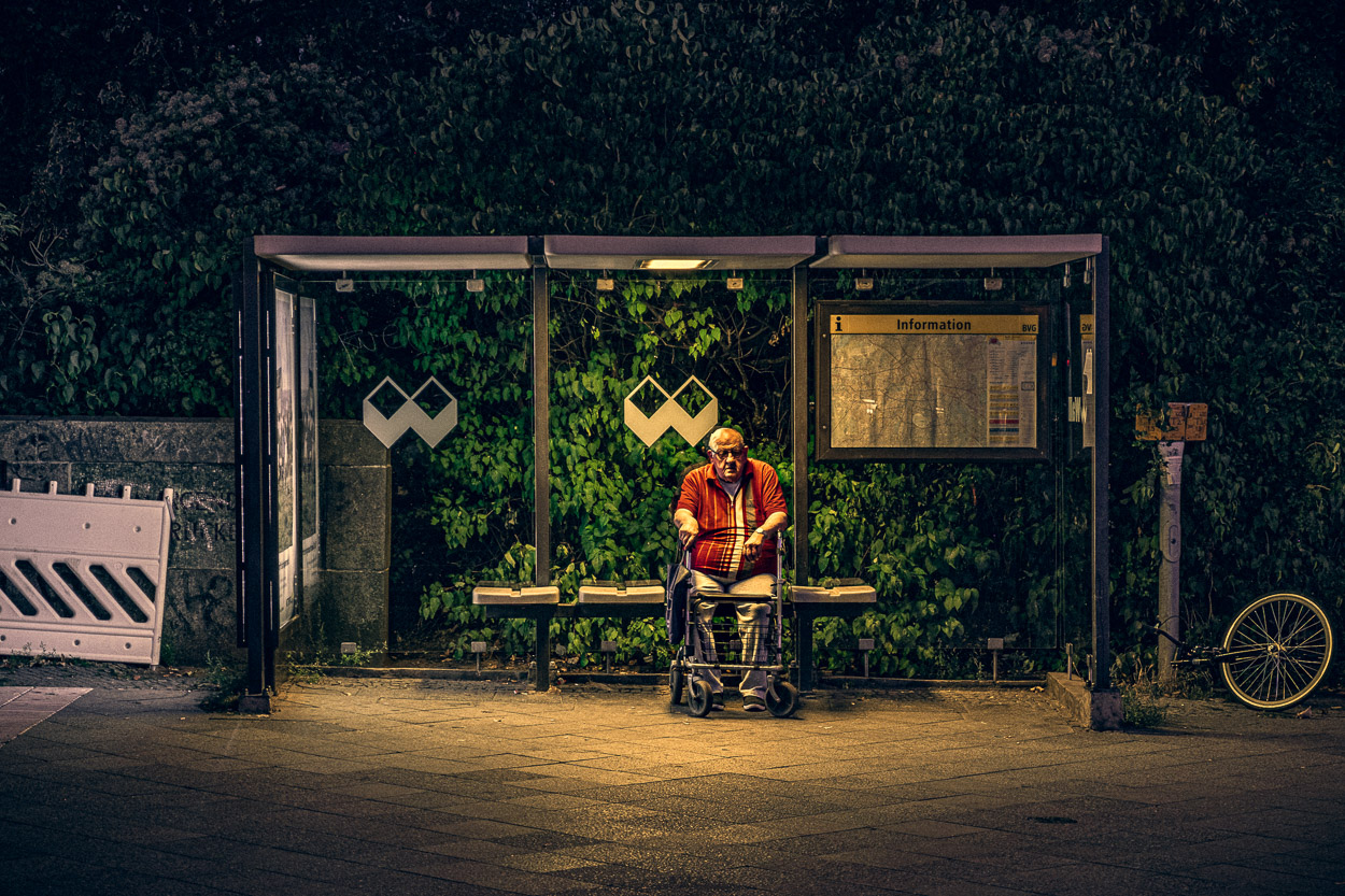 A man sitting on a bench at a bus stop.